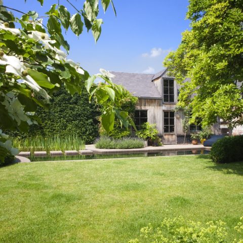 Exclusive swimming pond next to wooden pool house in city garden designed by Wirtz