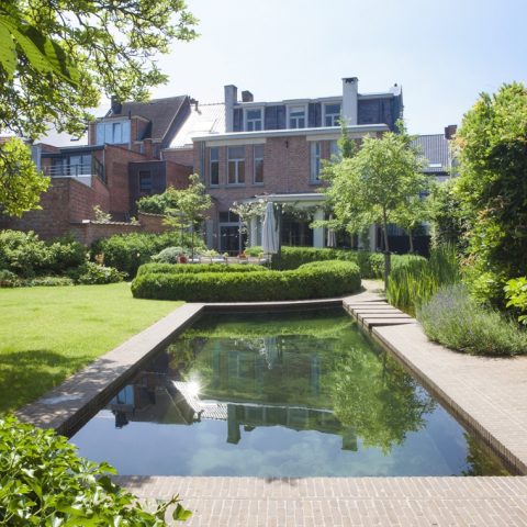 Exclusive swimming pond next to wooden pool house in city garden designed by Wirtz