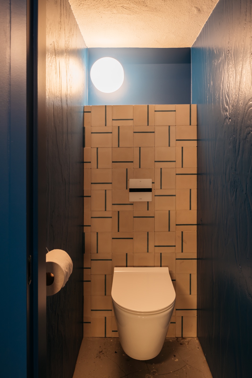 Modern beige tiles with blue motif, concrete floor, blue patterned walls, high-gloss white toilet ,Room,Indoors,Bathroom,Toilet,Shower,Corner,Shower Faucet,Toilet Paper,Meeting Room,Spa, Luxury, Design, Exclusive, Modern, Custom Made, Special, Beautiful