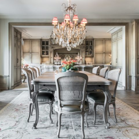 Historic living room inspiration, beige floral print rug, modern chandelier, grey wood dining table, grey ornate dining chairs with grey leather upholstery ,Stoel, Meubilair, Eetkamer, Kamer, Binnen, Kroonluchter, Lamp, Tafel, Eettafel, Huisvesting, Luxe, Design, Exclusief, Modern, Maatwerk, Bijzondere, Mooie