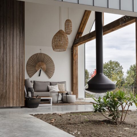 Concrete floor, wooden wall, luxury canopy with wooden beams, high-end white villa with black frames, luxury steel outdoor stove, wood with white steel frame with grey cushions, luxurious rattan lamps, wicker rug ,Interior Design,Indoors,Home Decor,Living Room,Furniture,Housing,House,Floor,Wood Panels,Couch, Luxury, Design, Exclusive, Modern, Custom Made, Special, Beautiful