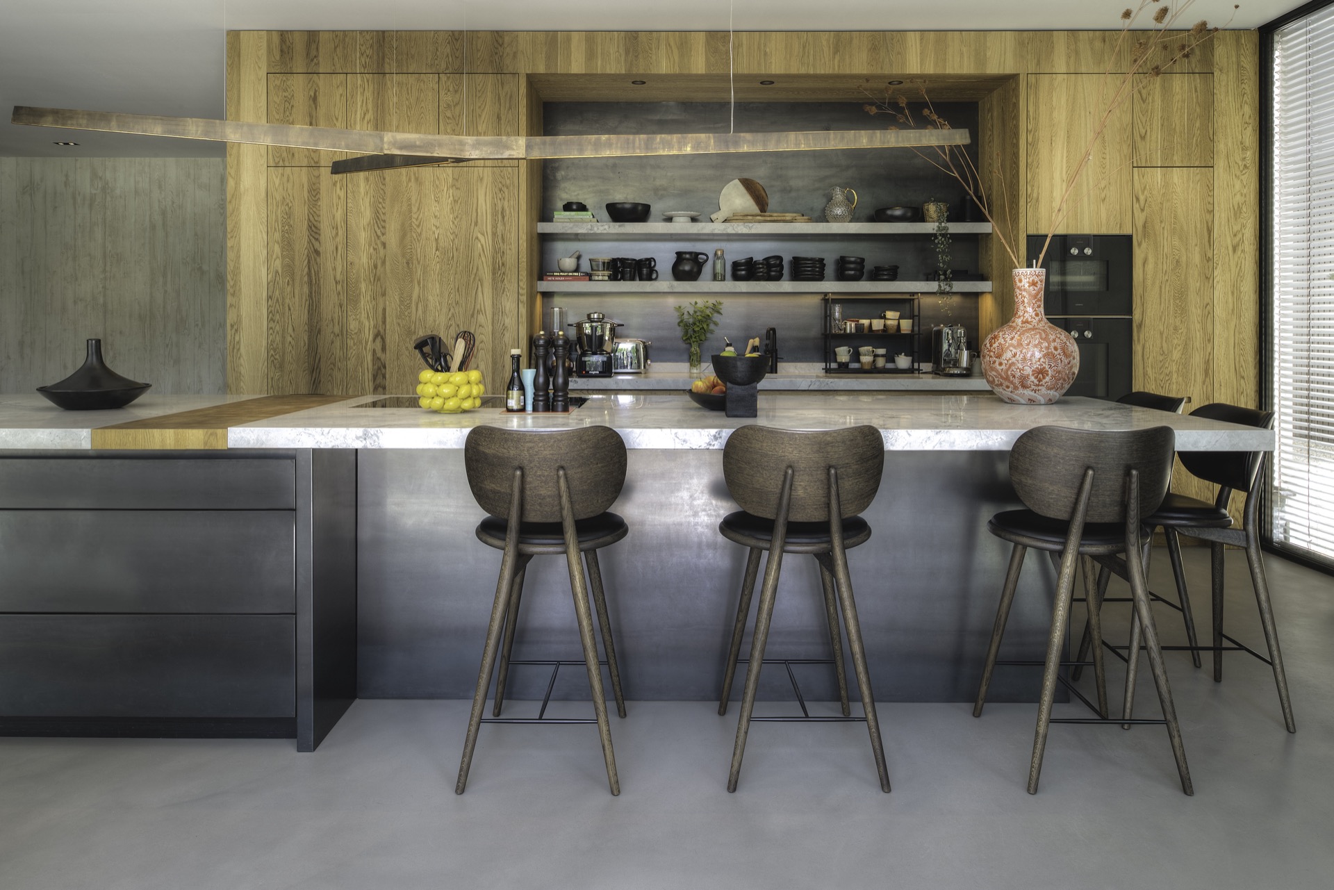 Gietvloer, donker houten barkrukken, luxe zilver metallic kookeiland met wit marmeren keukenblad, luxe houten keuken met metallic achterwand ,Interieurontwerp, Binnen, Keuken, Keukeneiland, Stoel, Meubels, Barkruk, Eettafel, Schep, Ananas, Luxe, Design, Exclusief, Modern, Maatwerk, Bijzondere, Mooie