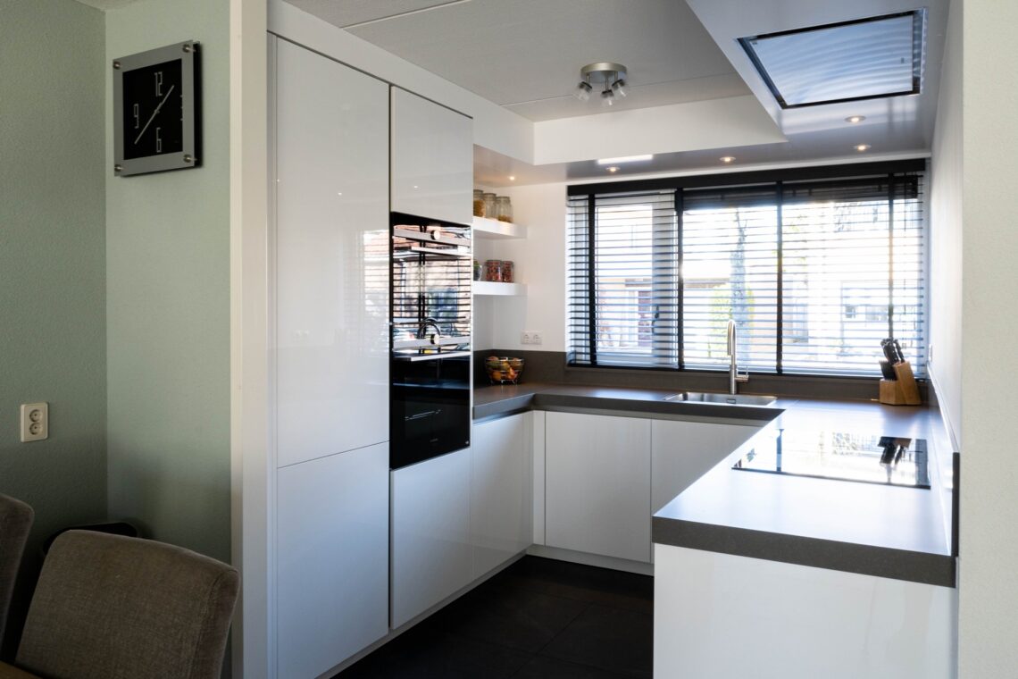 U-vorm keuken wit hoogglans met donker werkblad