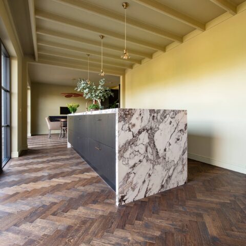 Dark oak herringbone floor with black kitchen and marble countertop