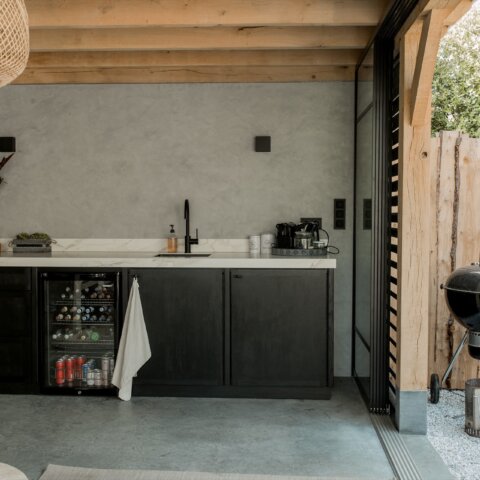 Moderne comfortabele buitenkeuken in sfeerrijke tuinkamer