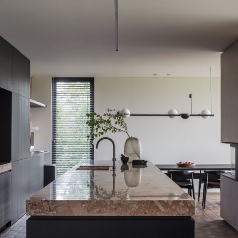 Rénovation créant une cuisine ouverte autour d’un îlot aspect marbre, bois et pierre intemporels