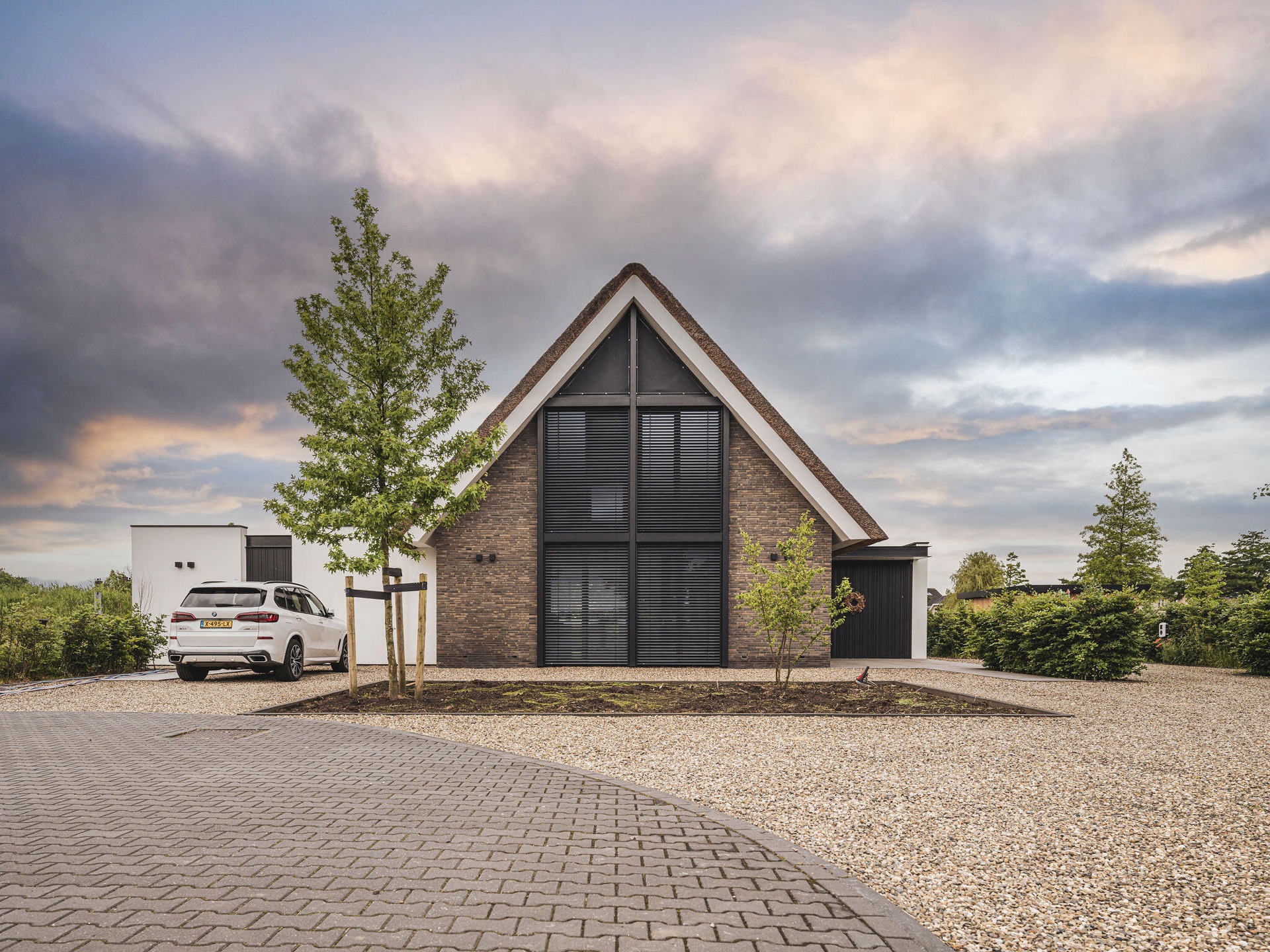 Villa mit Reetdach und Giebel: landhaus-Moderne Villa mit reetgedecktem Giebel, dunkler Ziegelwand und Lamellenfenstern, Luxury, Design, Exclusive, Modern, Custom Made, Special, Beautiful