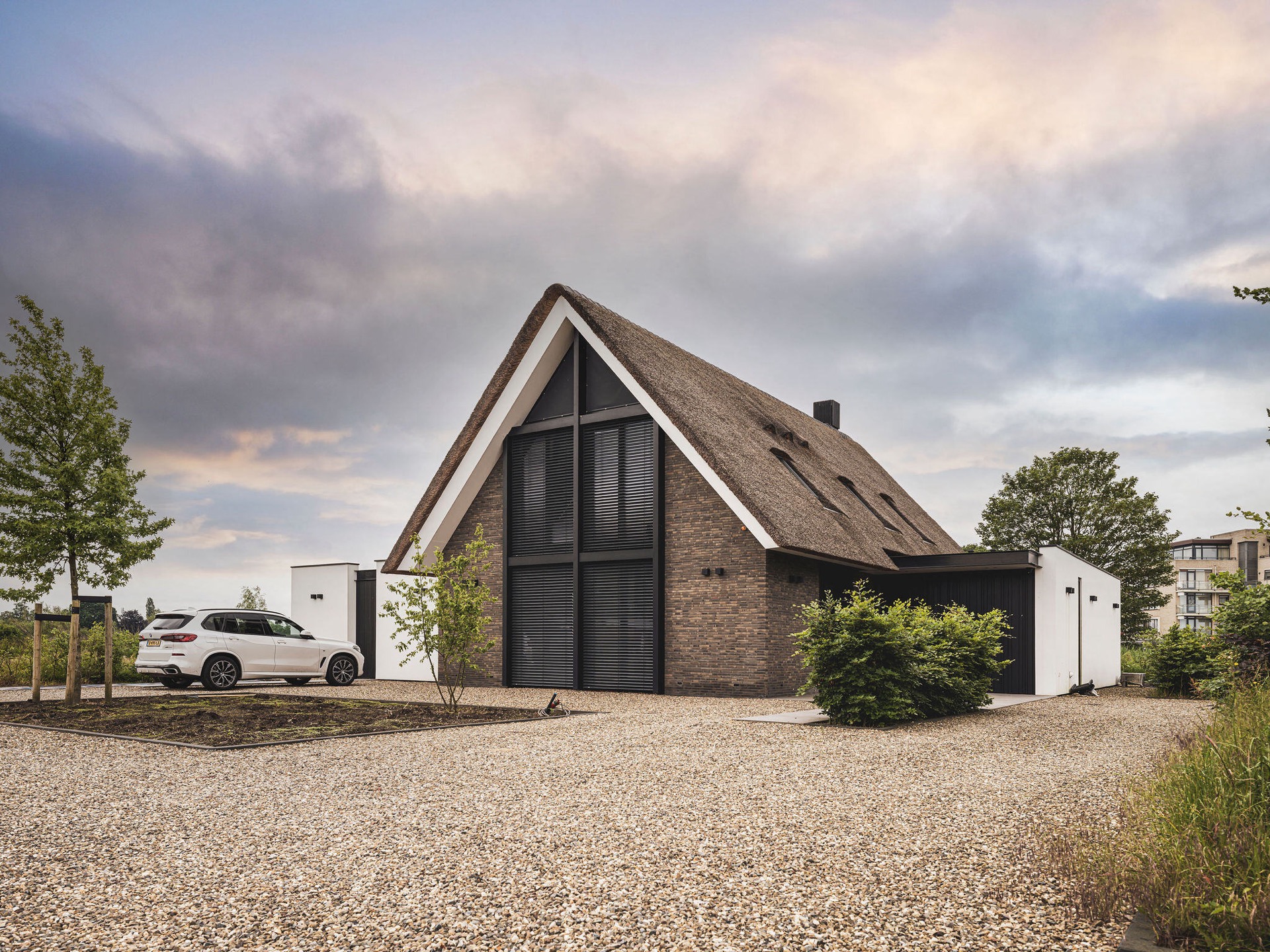 Villa mit Reetdach und Giebel: seitenansicht einer modernen Villa mit reetgedecktem Dach, dunkler Ziegelwand und, Luxury, Design, Exclusive, Modern, Custom Made, Special, Beautiful