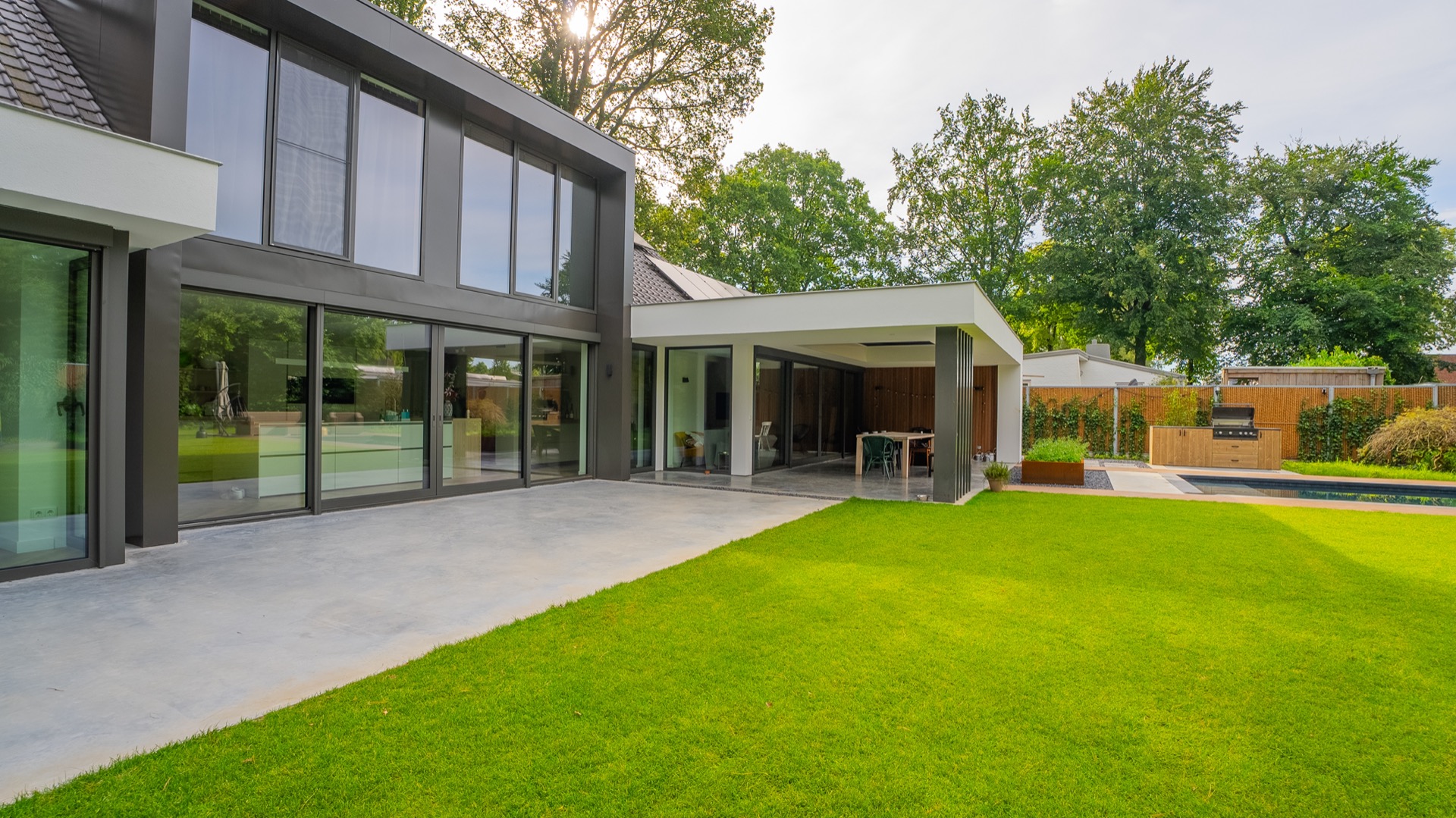 baukundiger Pool mit Betonterasse: sonniger Außenbereich mit Betonterasse, Glasfassade und Blick auf das Schwimmbecken, Luxury, Design, Exclusive, Modern, Custom Made, Special, Beautiful