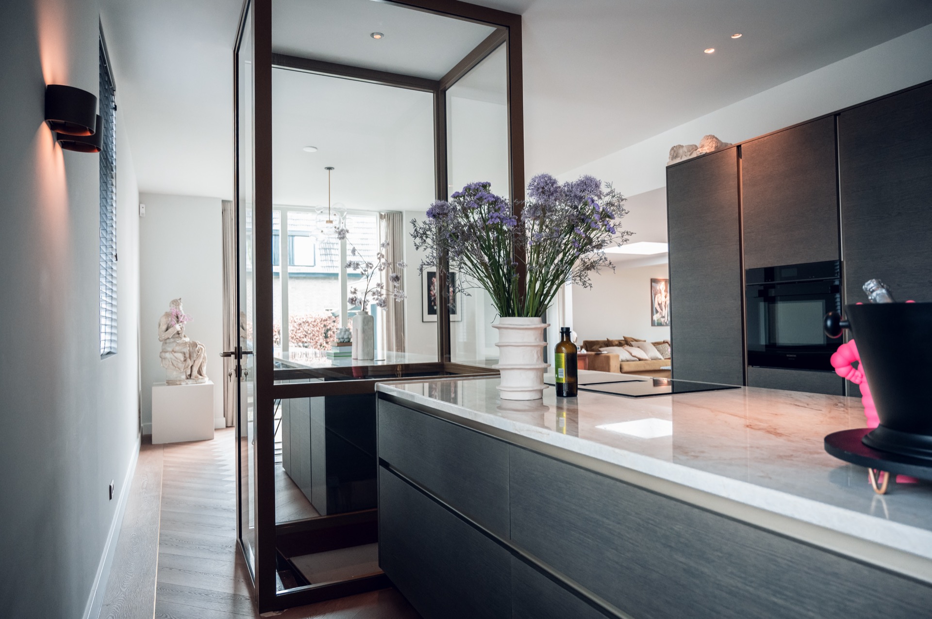 kitchen island with glass display and optical zoning: kitchen with glass frame across the island and view into the living, Luxury, Design, Exclusive, Modern, Custom Made, Special, Beautiful