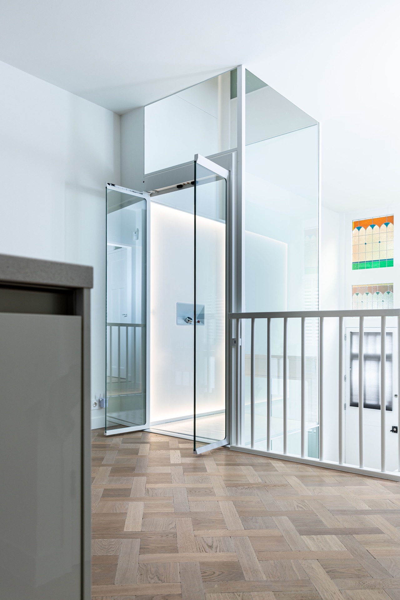 Glashomelift-Schacht: homelift mit Glaswänden und weißem Rahmen auf einer Etage mit Holzboden, Luxury, Design, Exclusive, Modern, Custom Made, Special, Beautiful