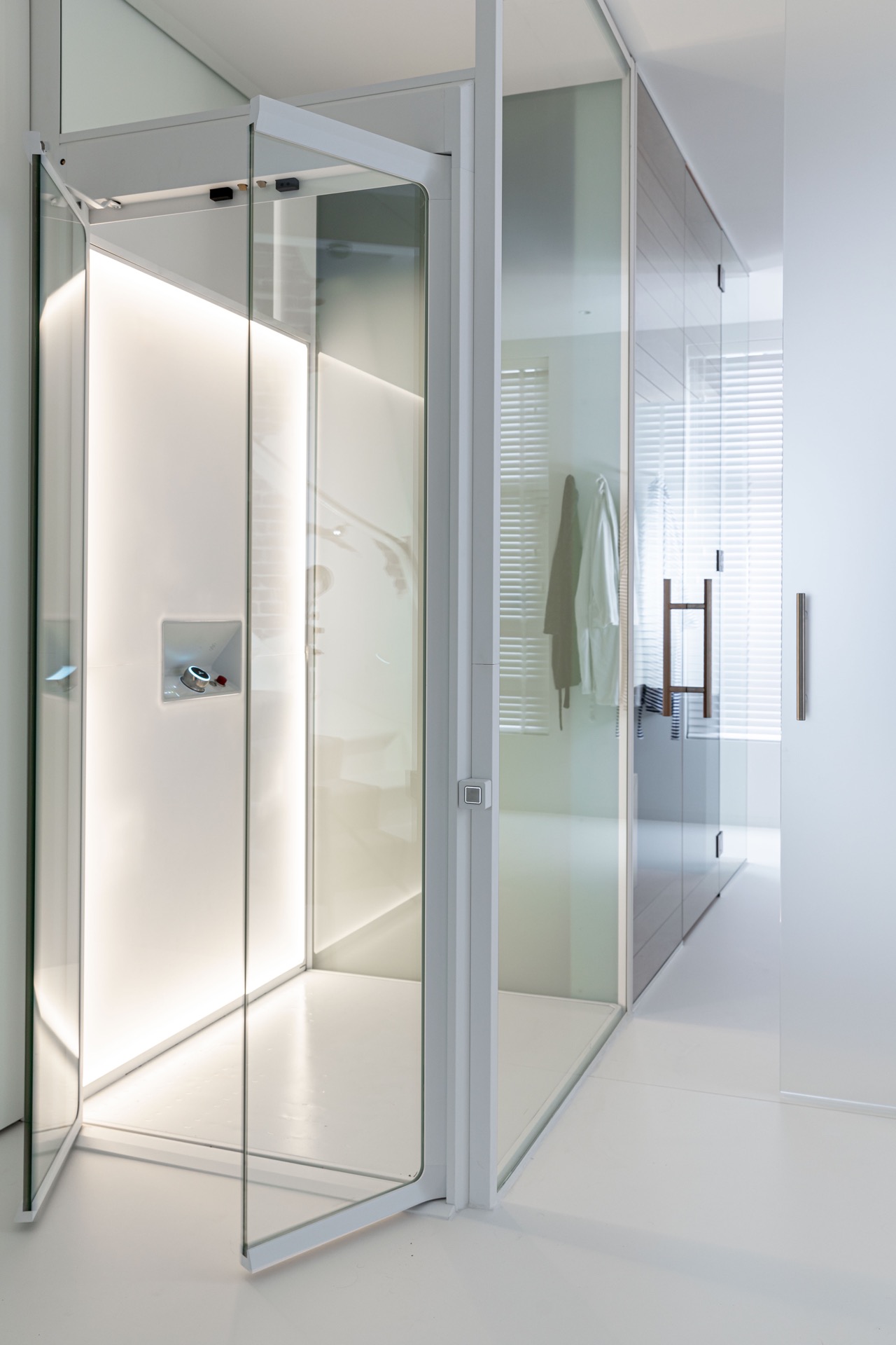 Glashomelift-Schacht: glastrennwand zwischen weißem Innenbereich und Holzsauna mit warmem Licht, Luxury, Design, Exclusive, Modern, Custom Made, Special, Beautiful