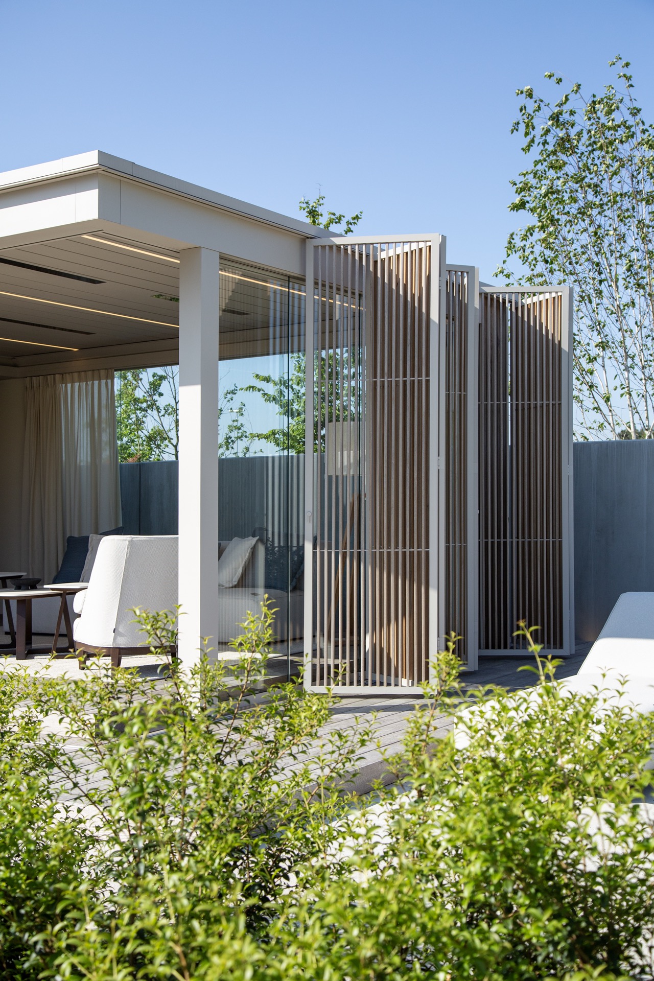 modernes Gartenhaus mit überdachter Terrasse: Überdachte Terrasse mit Glasfassade und vertikalen Lamellen als Sichtschutz, Luxury, Design, Exclusive, Modern, Custom Made, Special, Beautiful