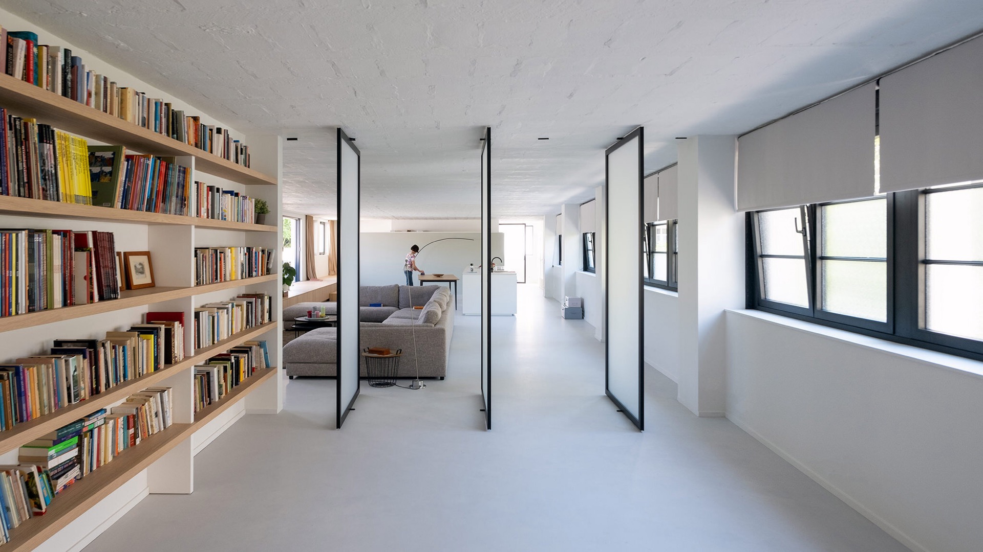 Porta pivot effetto acciaio in vetro in un soggiorno luminoso con librerie e cornici scure, Luxury, Design, Exclusive, Modern, Custom Made, Special, Beautiful