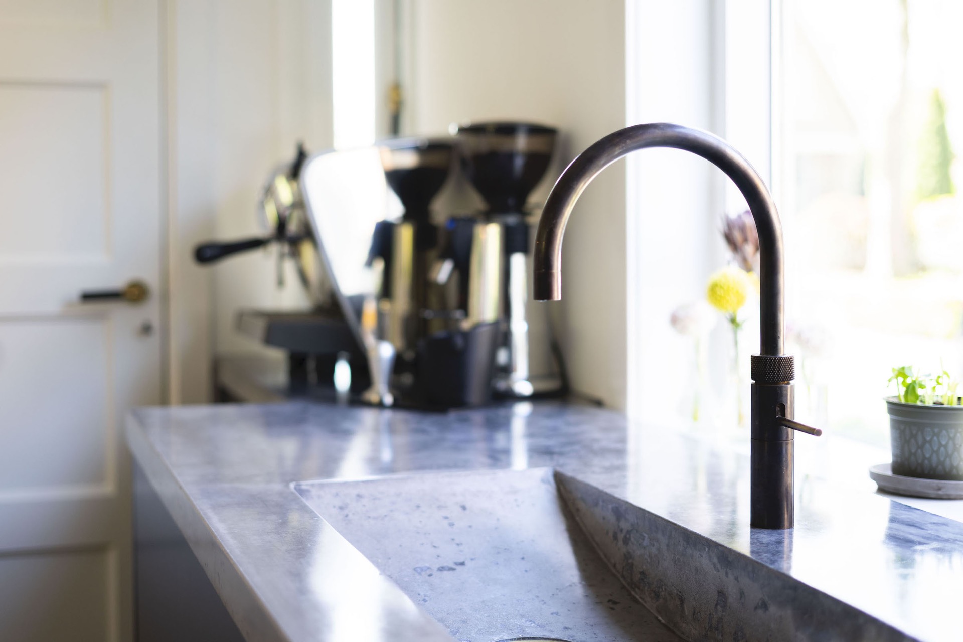 cucina su misura con isola e lavello integrato: primo piano del rubinetto con getto d’acqua su piano cucina scuro, Luxury, Design, Exclusive, Modern, Custom Made, Special, Beautiful