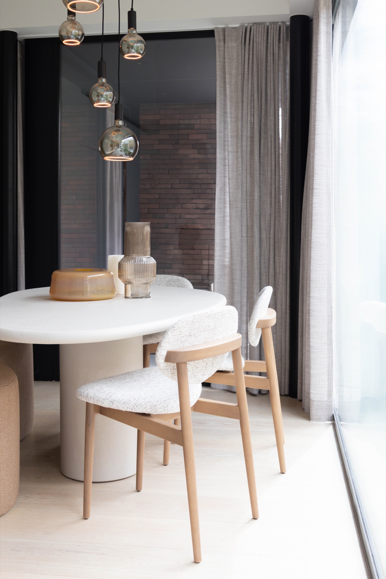 interno minimalista caldo su misura: zona pranzo con tavolo rotondo bianco, sedie beige, tende grigie e parete in mattoni a, Luxe, Design, Exclusief, Modern, Maatwerk, Bijzondere, Mooie