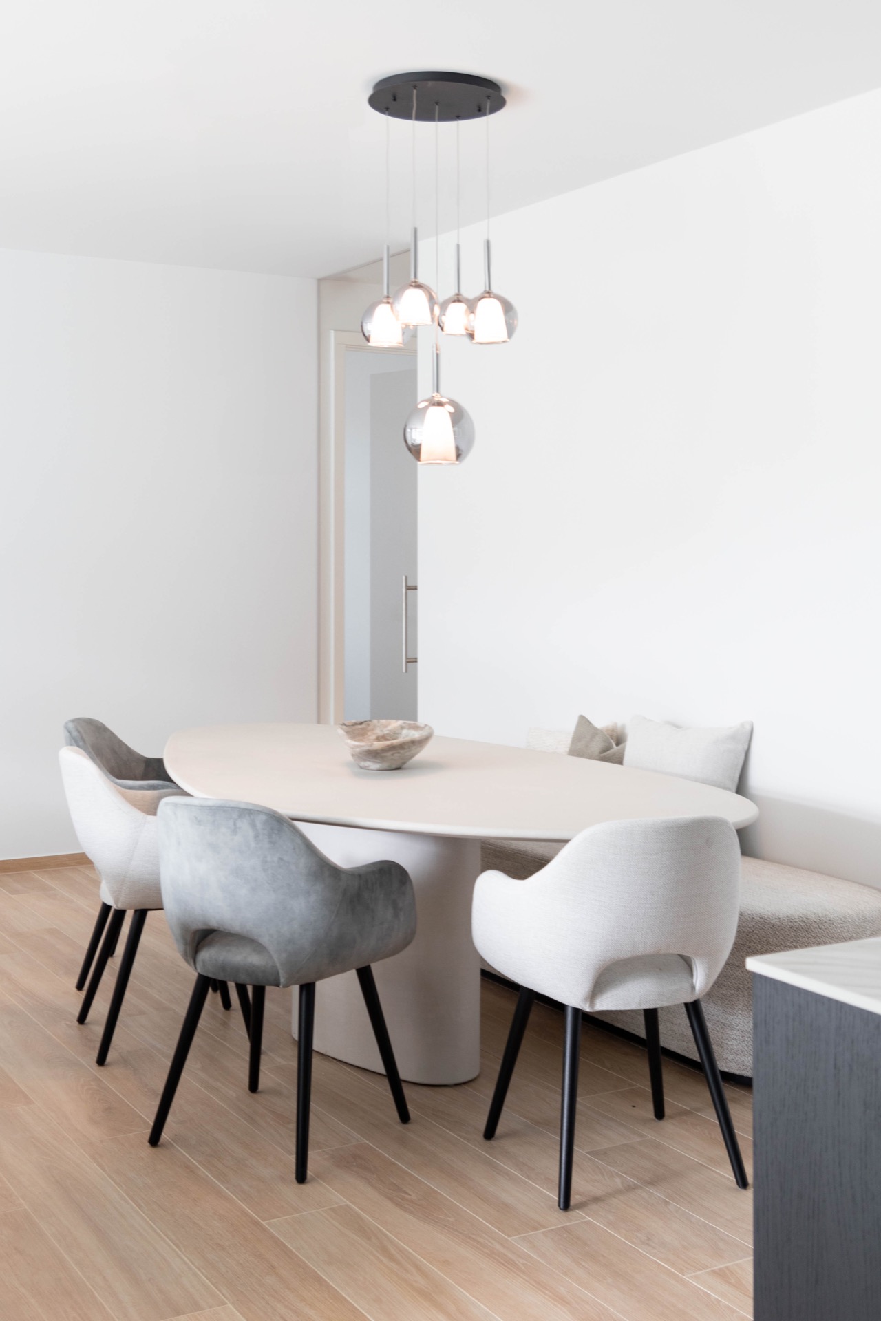 interno arioso con colori neutri: zona pranzo con tavolo rotondo, sedie imbottite e più lampade a sospensione in vetro, Luxury, Design, Exclusive, Modern, Custom Made, Special, Beautiful