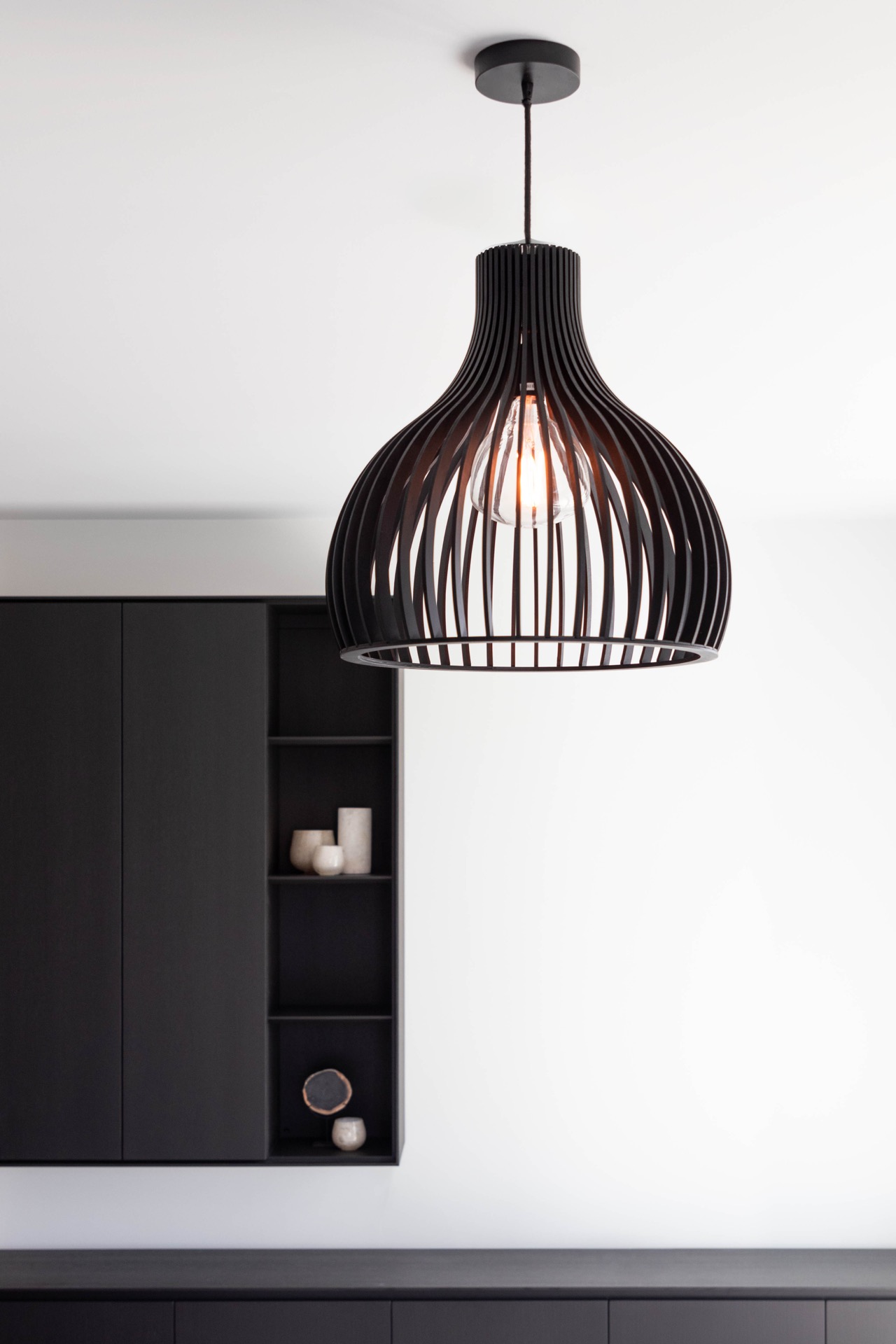 interno arioso con colori neutri: dettaglio della lampada a sospensione di design nera con struttura aperta e lampadina, Luxury, Design, Exclusive, Modern, Custom Made, Special, Beautiful