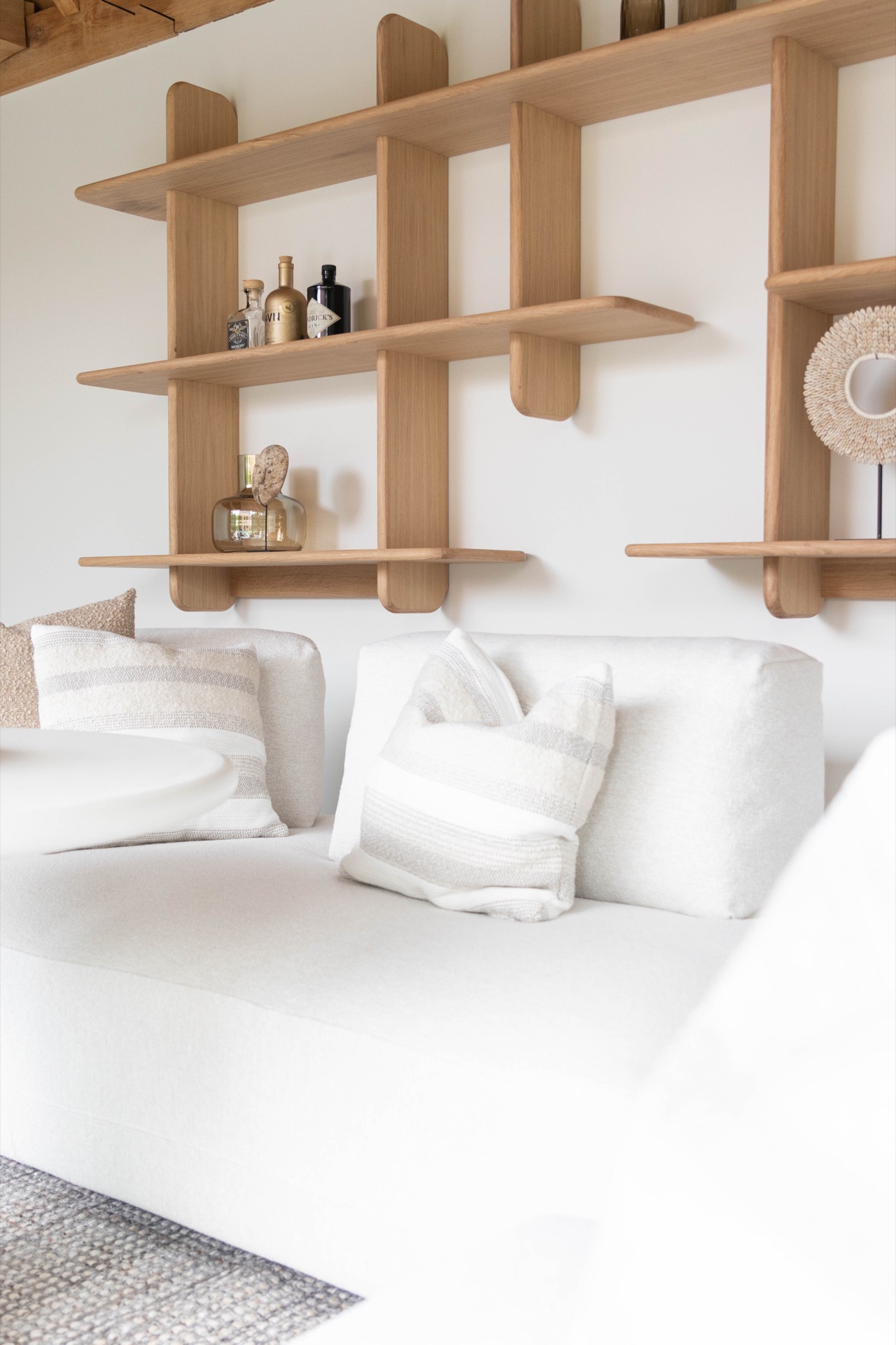 poolhouse con tetto in paglia: divano bianco e cuscini nel poolhouse con parete di mensole in legno sullo sfondo, Luxury, Design, Exclusive, Modern, Custom Made, Special, Beautiful