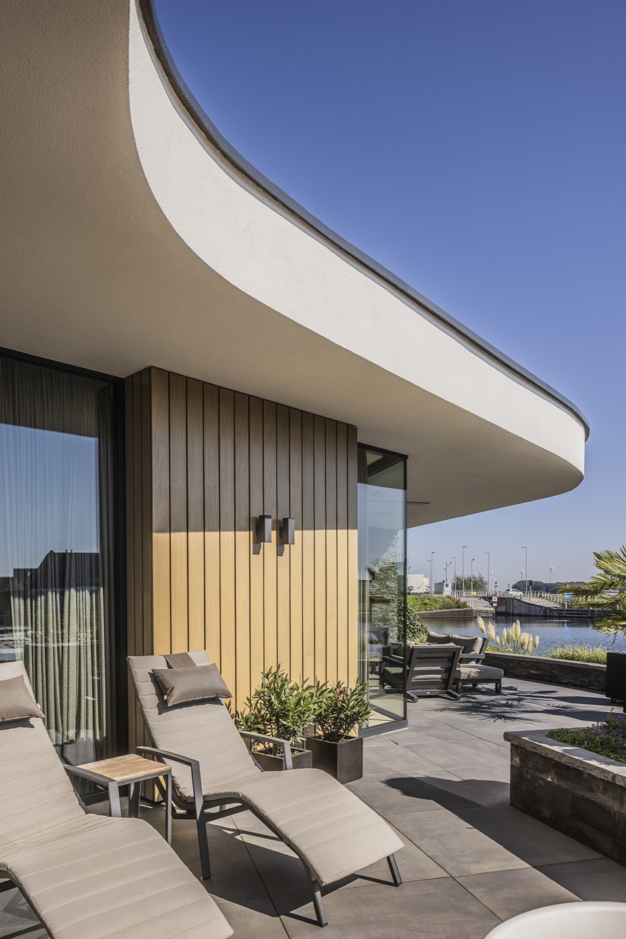 villa moderna sul lungomare: terrazza soleggiata a Villa Miami con lettini e pensilina curva verso l’acqua, Luxury, Design, Exclusive, Modern, Custom Made, Special, Beautiful