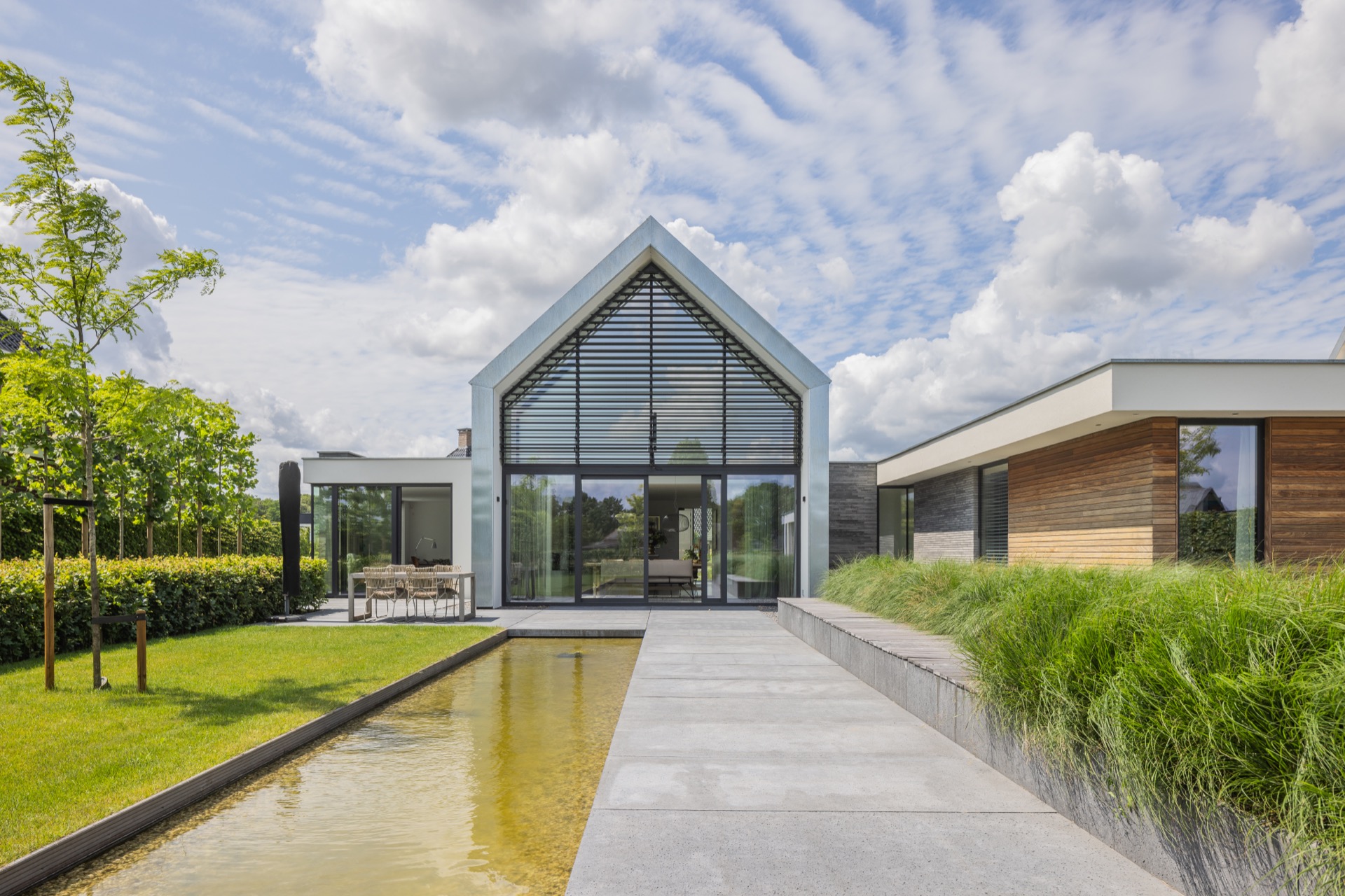 villa con accento facciata tipo zinco: giardino con striscia d’acqua riflettente e villa moderna con lamelle sopra la vetrata, Luxe, Design, Exclusief, Modern, Maatwerk, Bijzondere, Mooie