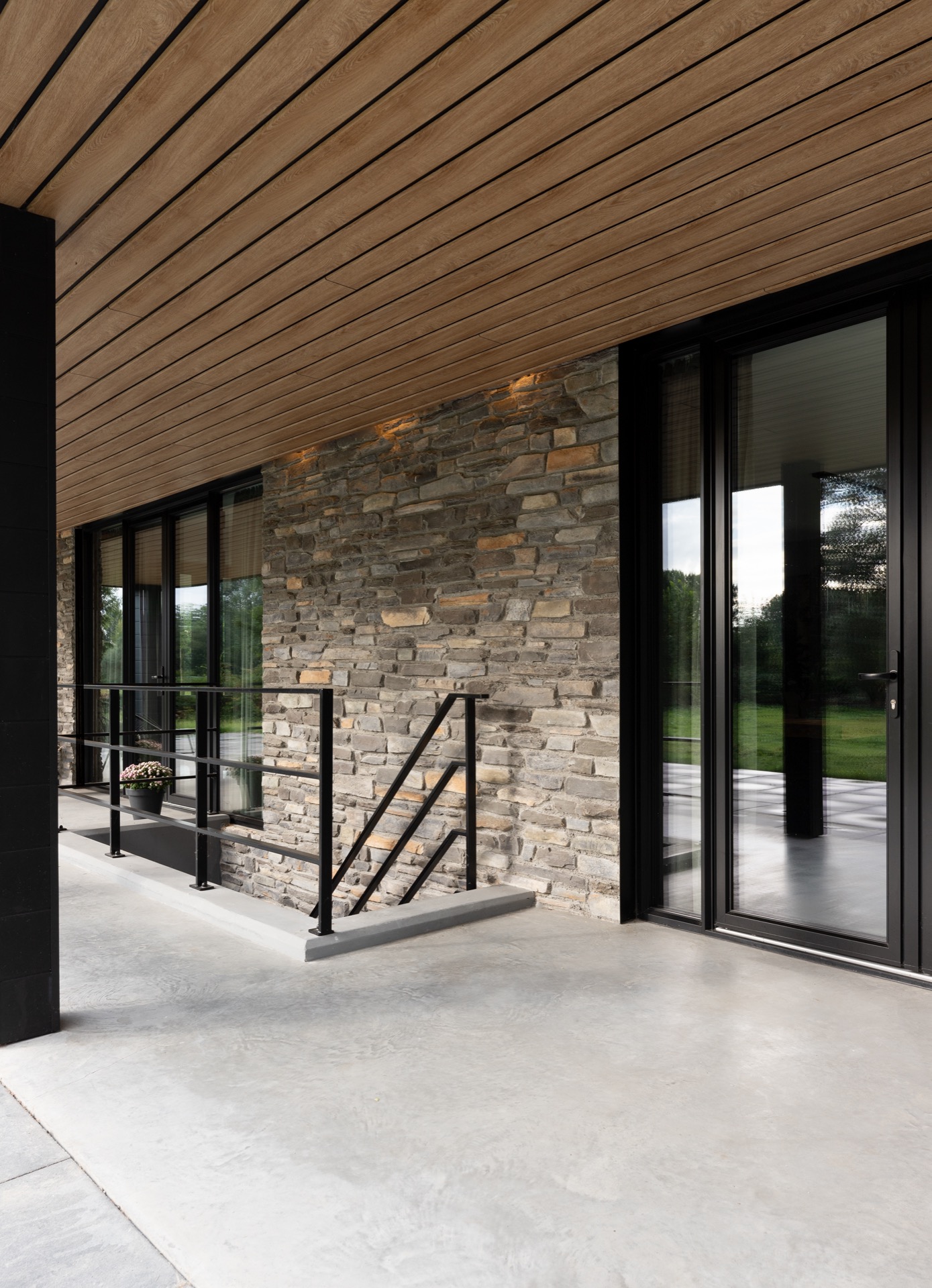 modern home natural stone strip cladding: glass facade section with natural stone wall and black frames under a covered, Luxe, Design, Exclusief, Modern, Maatwerk, Bijzondere, Mooie