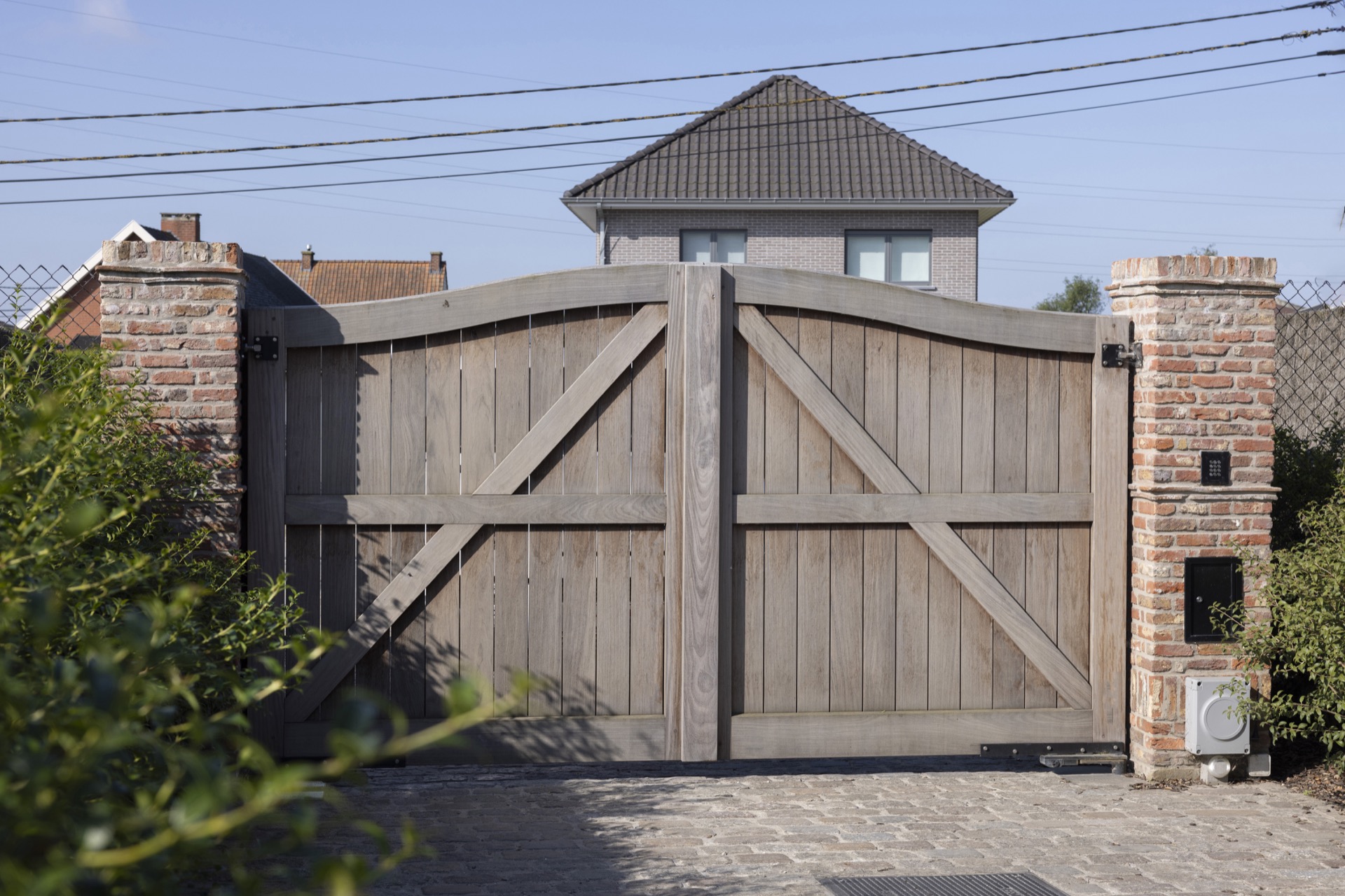 Afrormosia wood joinery project: large wooden gate with vertical boards and brick pillars in a fence line, Luxe, Design, Exclusief, Modern, Maatwerk, Bijzondere, Mooie