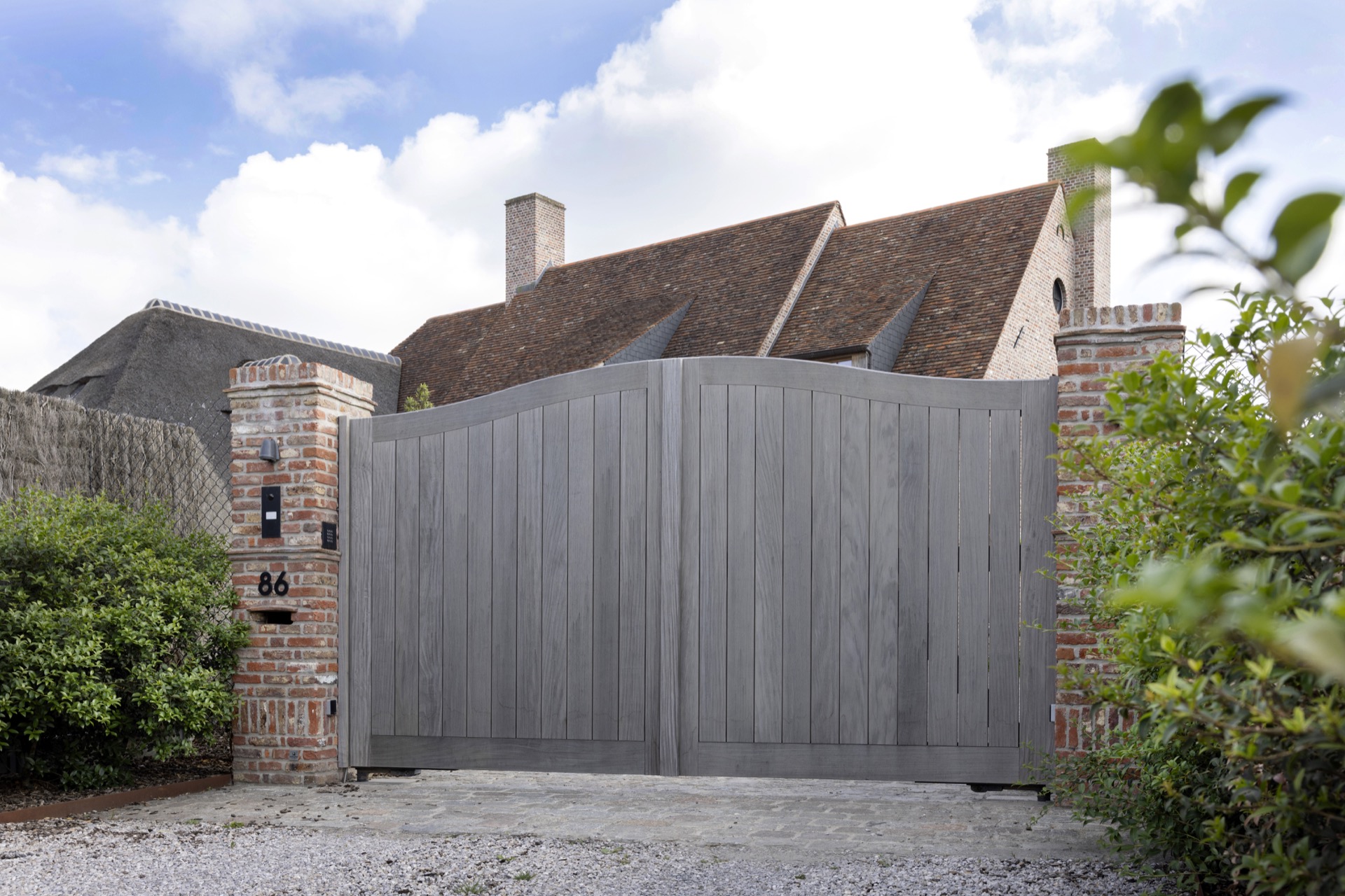Afrormosia wood joinery project: back view with a large gray wooden gate in a fence line and brick pillars, Luxe, Design, Exclusief, Modern, Maatwerk, Bijzondere, Mooie