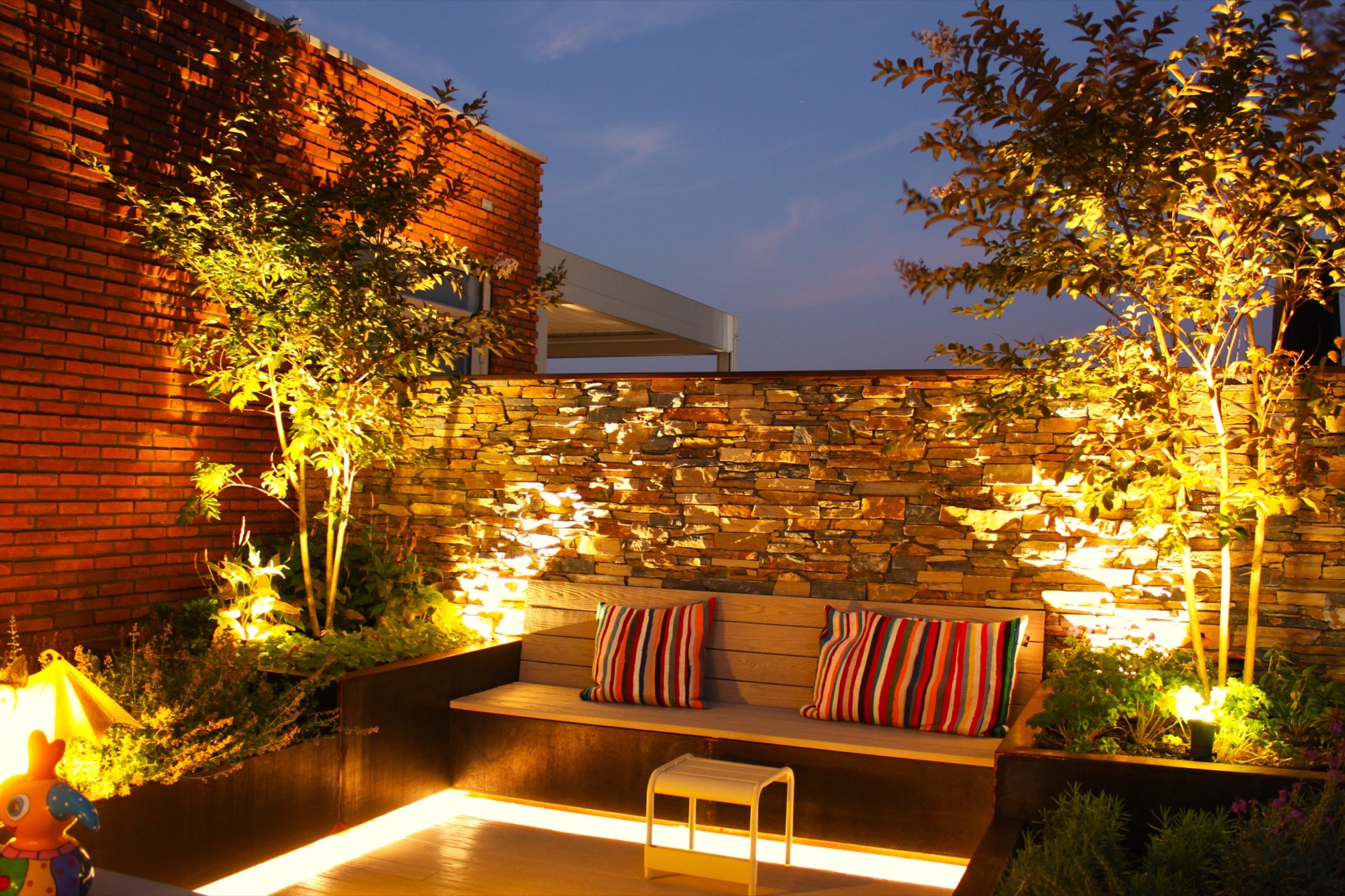 giardino pensile illuminazione: giardino pensile di sera con muro in pietra naturale, piante illuminate e panca in legno, Luxury, Design, Exclusive, Modern, Custom Made, Special, Beautiful