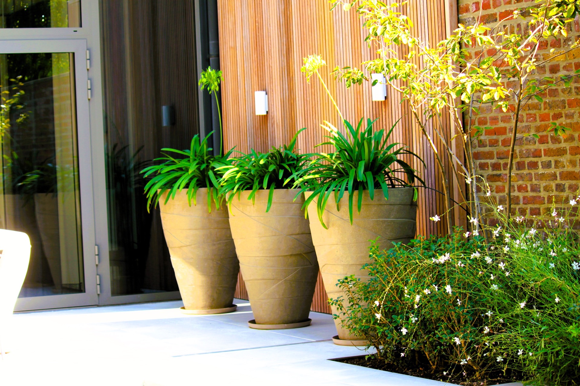 pool lounge area: plants in large grey planters along a wooden facade and brick wall in the patio garden, Luxury, Design, Exclusive, Modern, Custom Made, Special, Beautiful