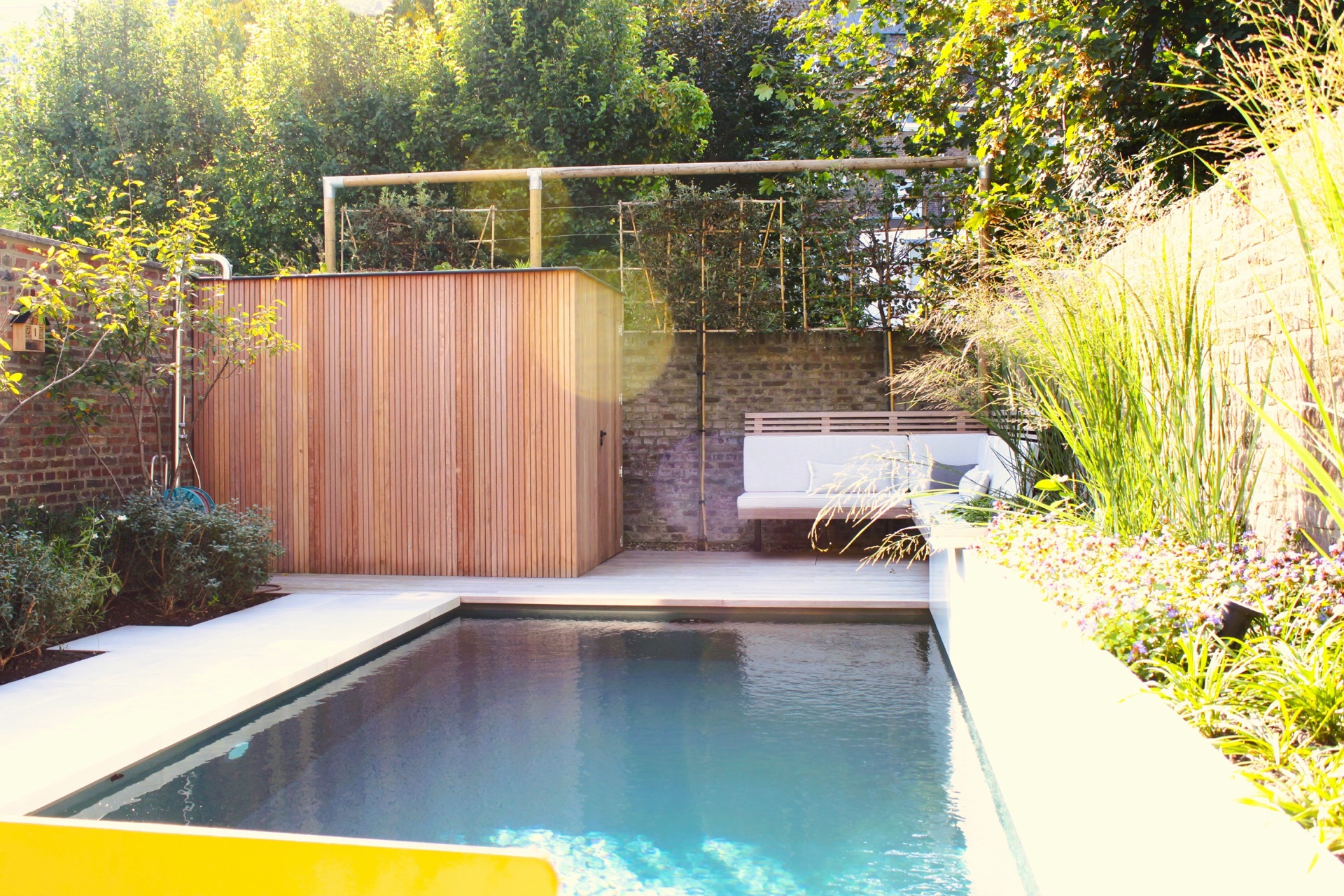 pool lounge area: patio garden with pool, terrace edges and lounge bench against a brick wall and wooden screens, Luxury, Design, Exclusive, Modern, Custom Made, Special, Beautiful