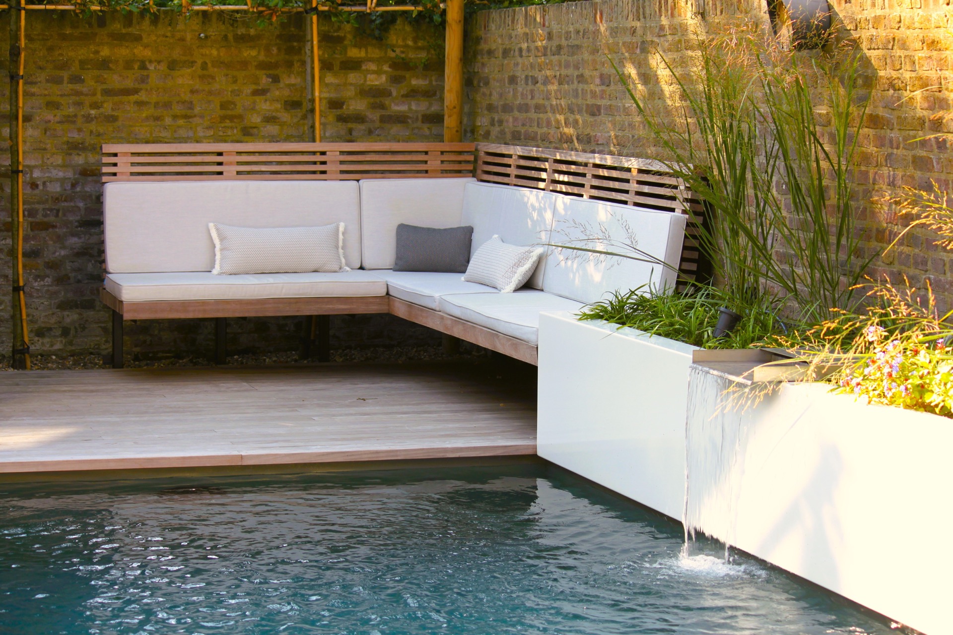 pool lounge area: lounge bench with wooden frame along the pool with white edging against a brick wall, Luxury, Design, Exclusive, Modern, Custom Made, Special, Beautiful