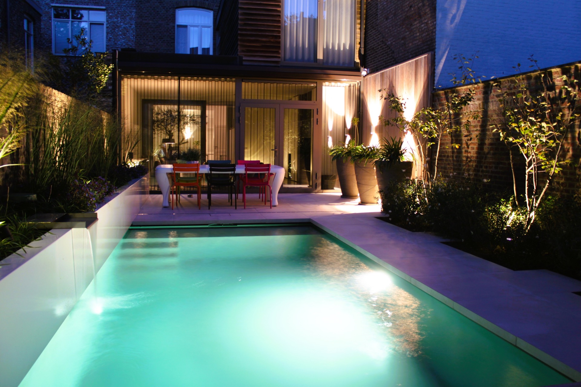 pool lounge area: evening view of patio garden with swimming pool, ceramic paving, brick walls and ambience lighting, Luxury, Design, Exclusive, Modern, Custom Made, Special, Beautiful
