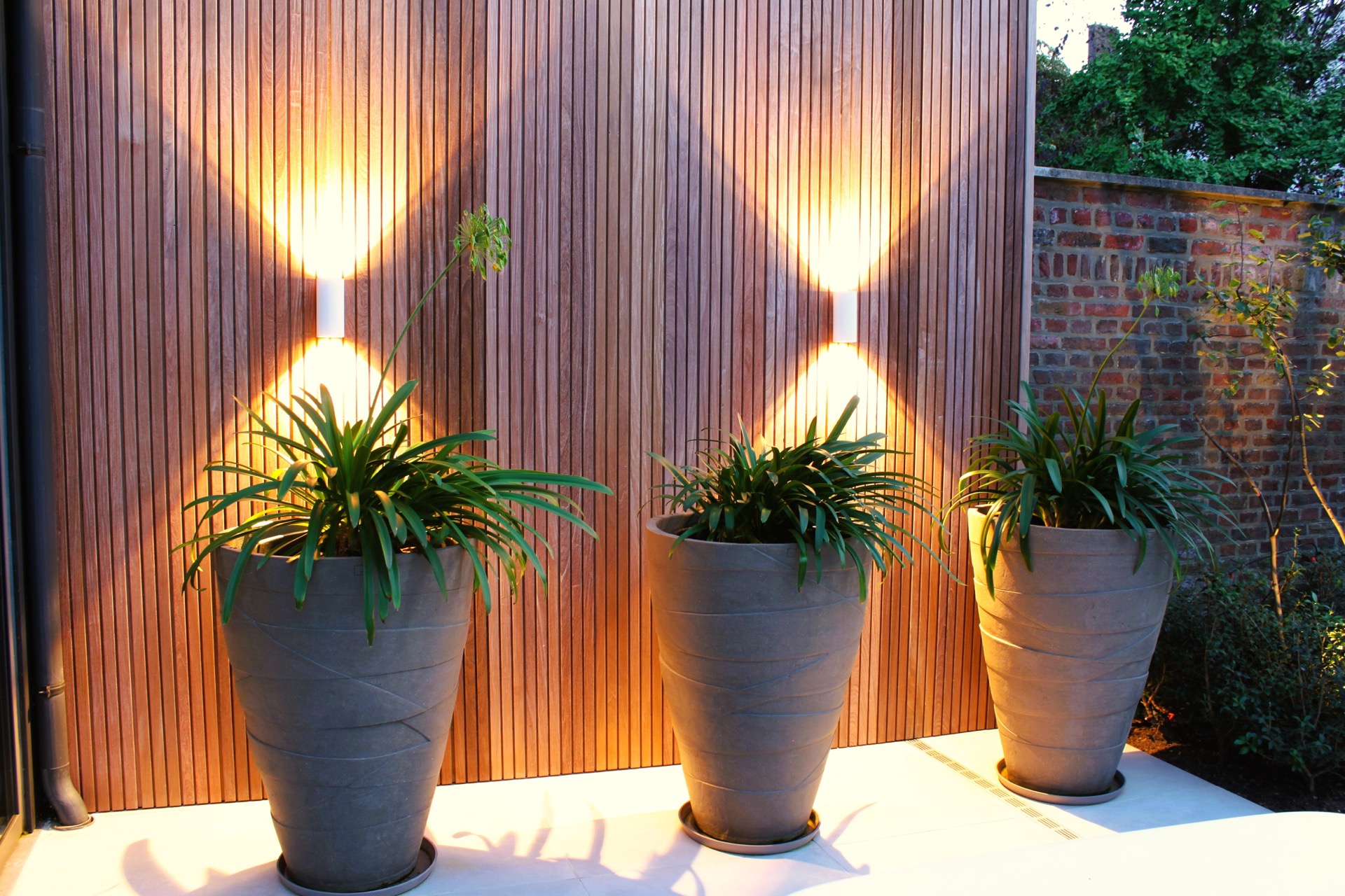 pool lounge area: tall grey planters against an illuminated wooden slat wall in the patio garden, Luxury, Design, Exclusive, Modern, Custom Made, Special, Beautiful