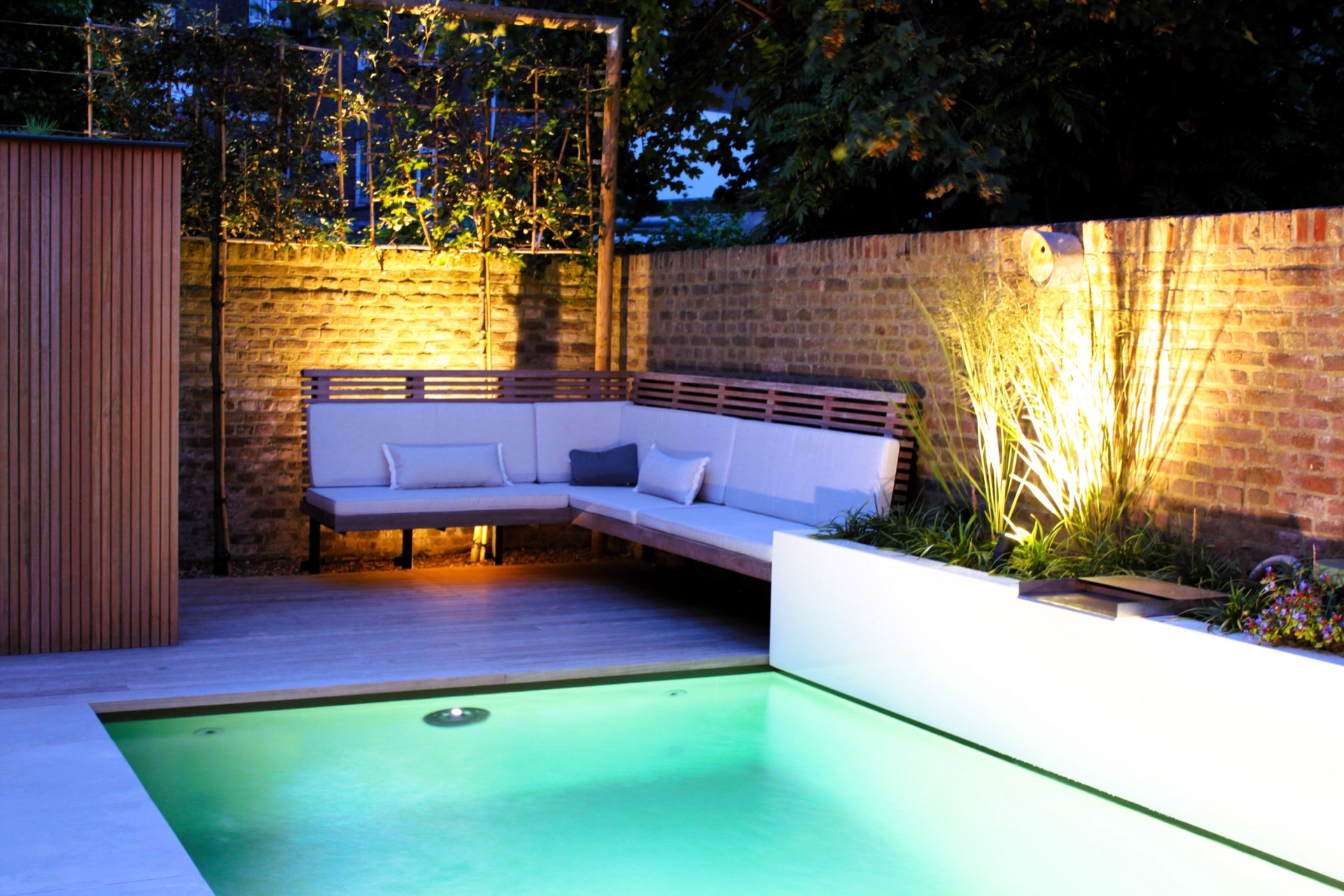 pool lounge area: evening view of patio garden with pool lighting, lounge bench and warm wall lighting on brick, Luxury, Design, Exclusive, Modern, Custom Made, Special, Beautiful