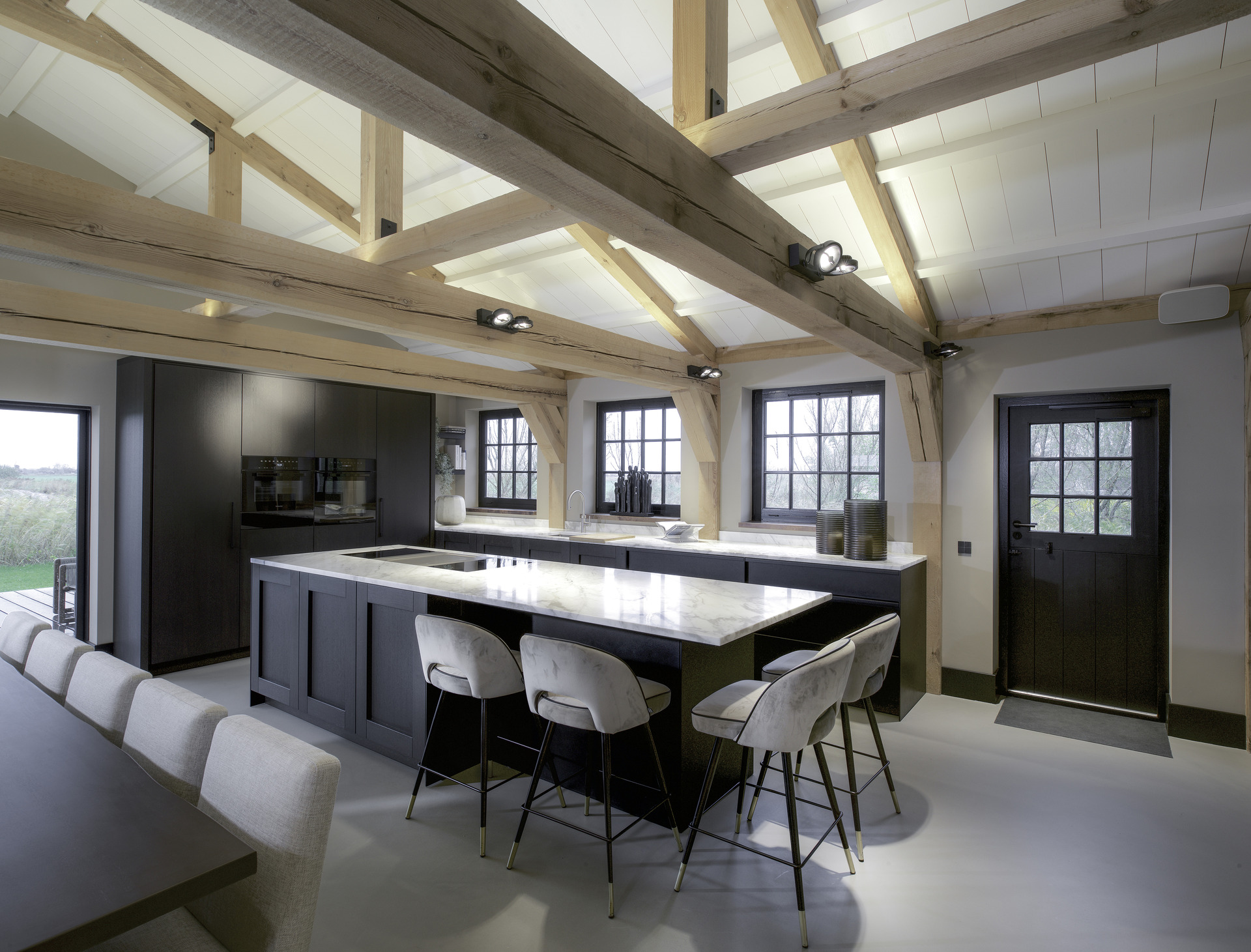 interno casa colonica unico: cucina con isola e piano di lavoro in pietra chiara sotto travi in legno e grandi finestre, Luxury, Design, Exclusive, Modern, Custom Made, Special, Beautiful