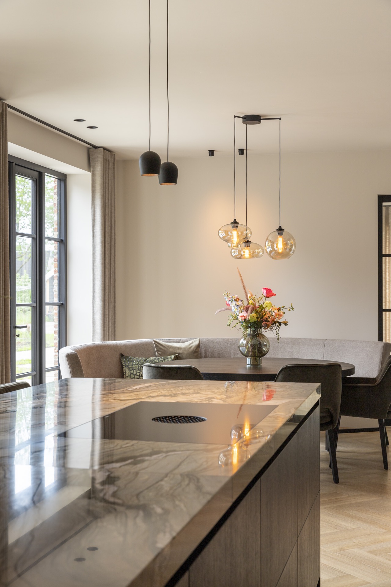 isola cucina con piano in pietra naturale: luci a sospensione sopra il tavolo da pranzo in uno spazio open con luce calda e, Luxury, Design, Exclusive, Modern, Custom Made, Special, Beautiful