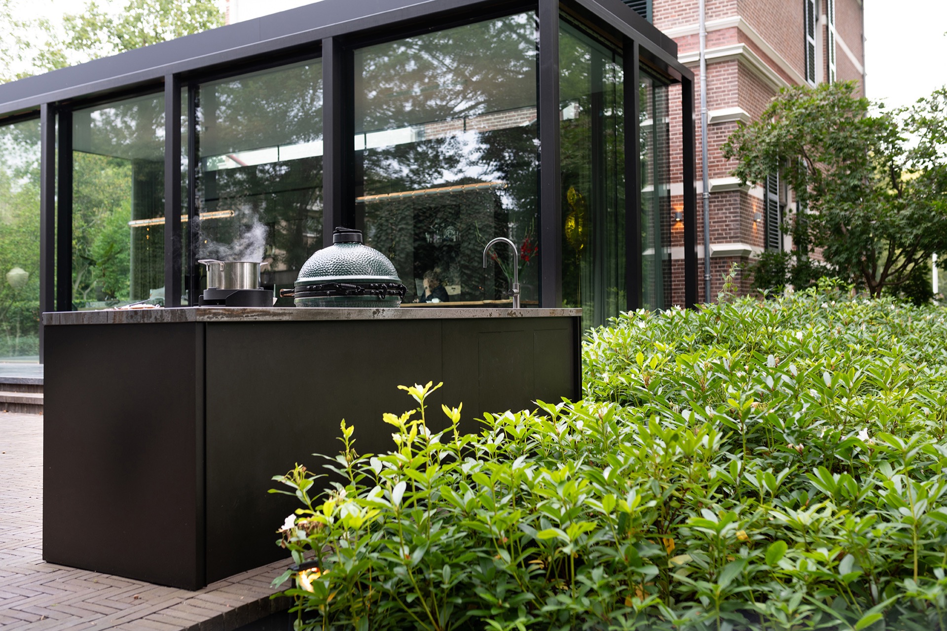 modern outdoor kitchen with natural stone worktop: glass canopy with outdoor kitchen and view of a brick facade, Luxury, Design, Exclusive, Modern, Custom Made, Special, Beautiful