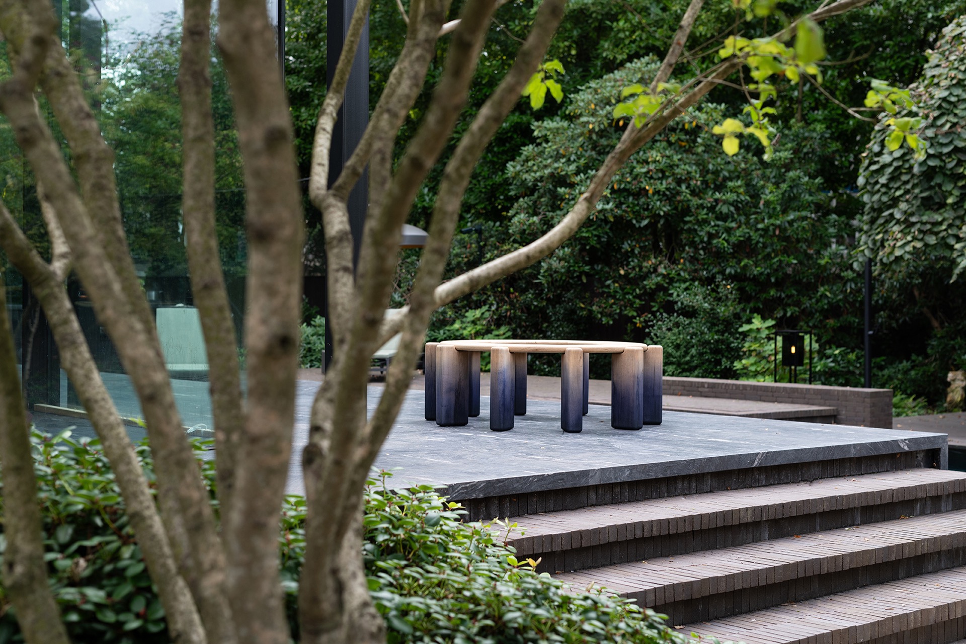 modern outdoor kitchen with natural stone worktop: terrace and water edge with a view of the outdoor kitchen through trees, Luxury, Design, Exclusive, Modern, Custom Made, Special, Beautiful