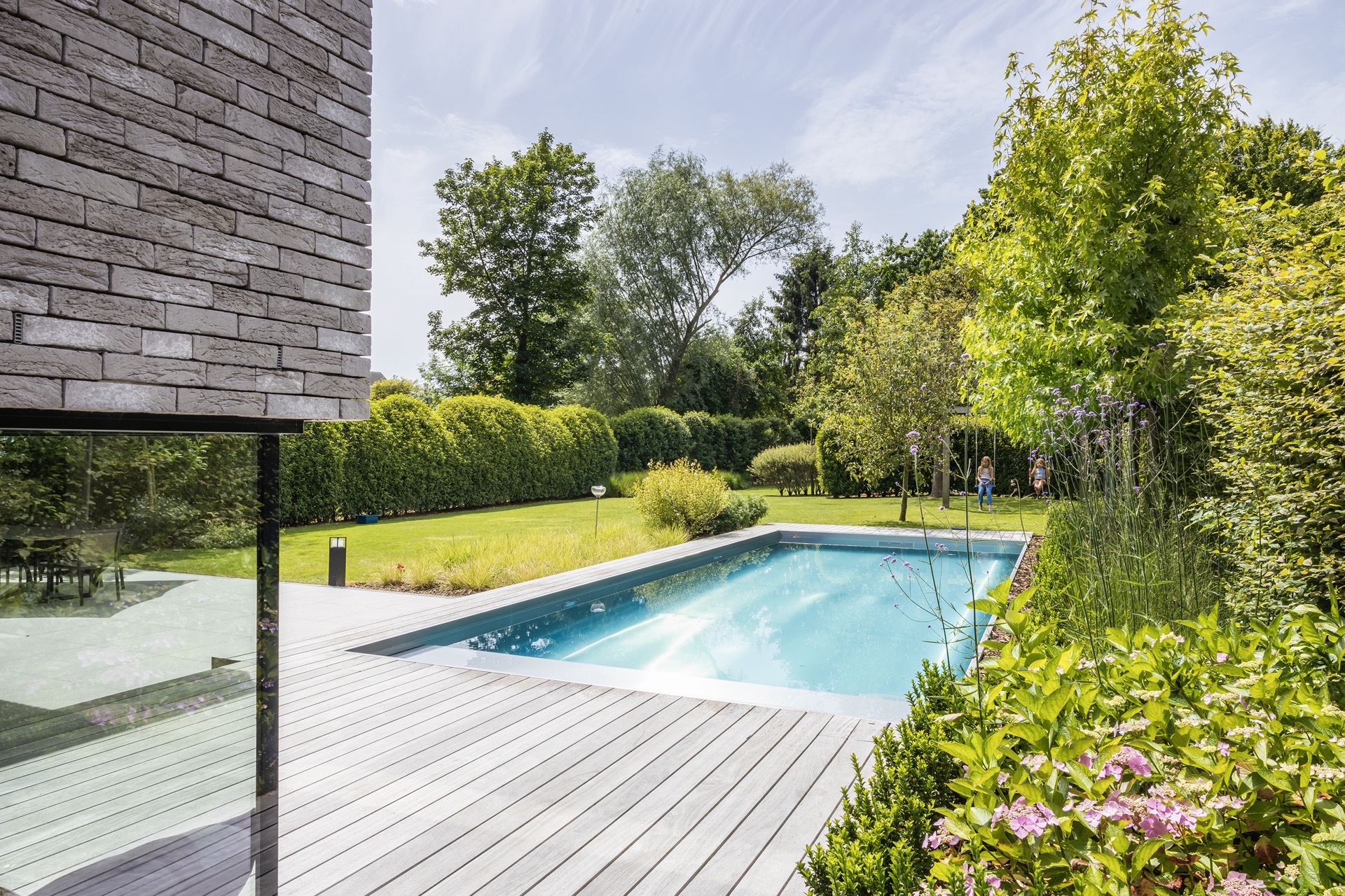 piscina in acciaio inox 10x4 m: piscina con pavimentazione in legno e facciata in mattoni moderno, circondata dal verde, Luxury, Design, Exclusive, Modern, Custom Made, Special, Beautiful