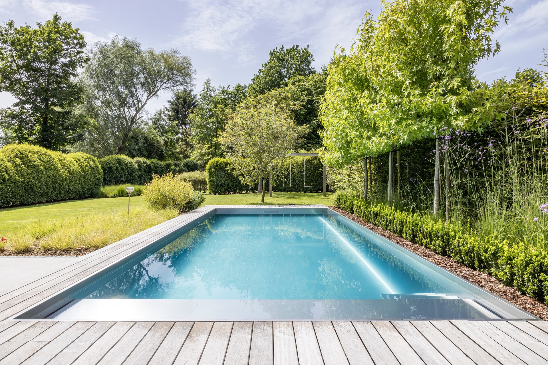 piscina in acciaio inox 10x4 m: piscina in acciaio inox in giardino curato con terrazza in legno e vista sull’acqua, Luxury, Design, Exclusive, Modern, Custom Made, Special, Beautiful
