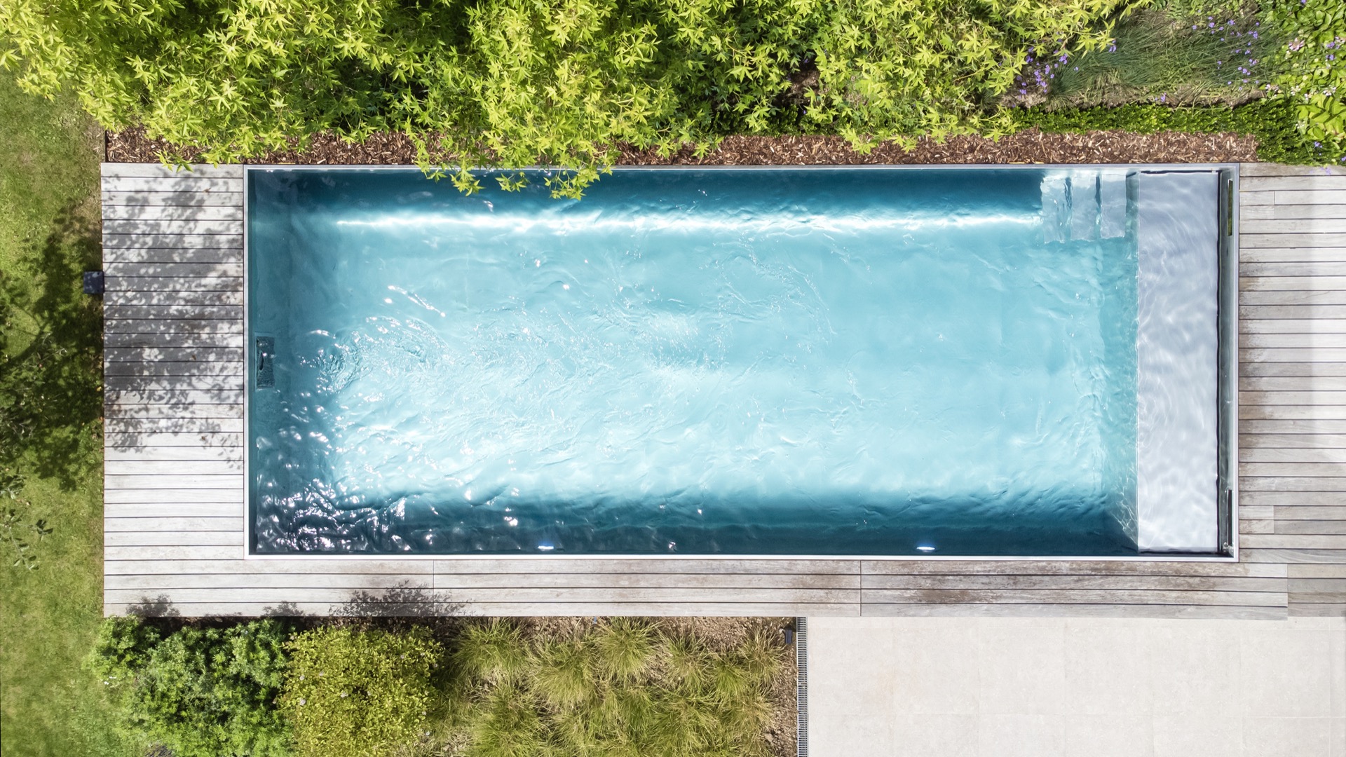 piscina in acciaio inox 10x4 m: vista longitudinale della piscina in acciaio inox con bordi puliti e vegetazione di giardino, Luxury, Design, Exclusive, Modern, Custom Made, Special, Beautiful