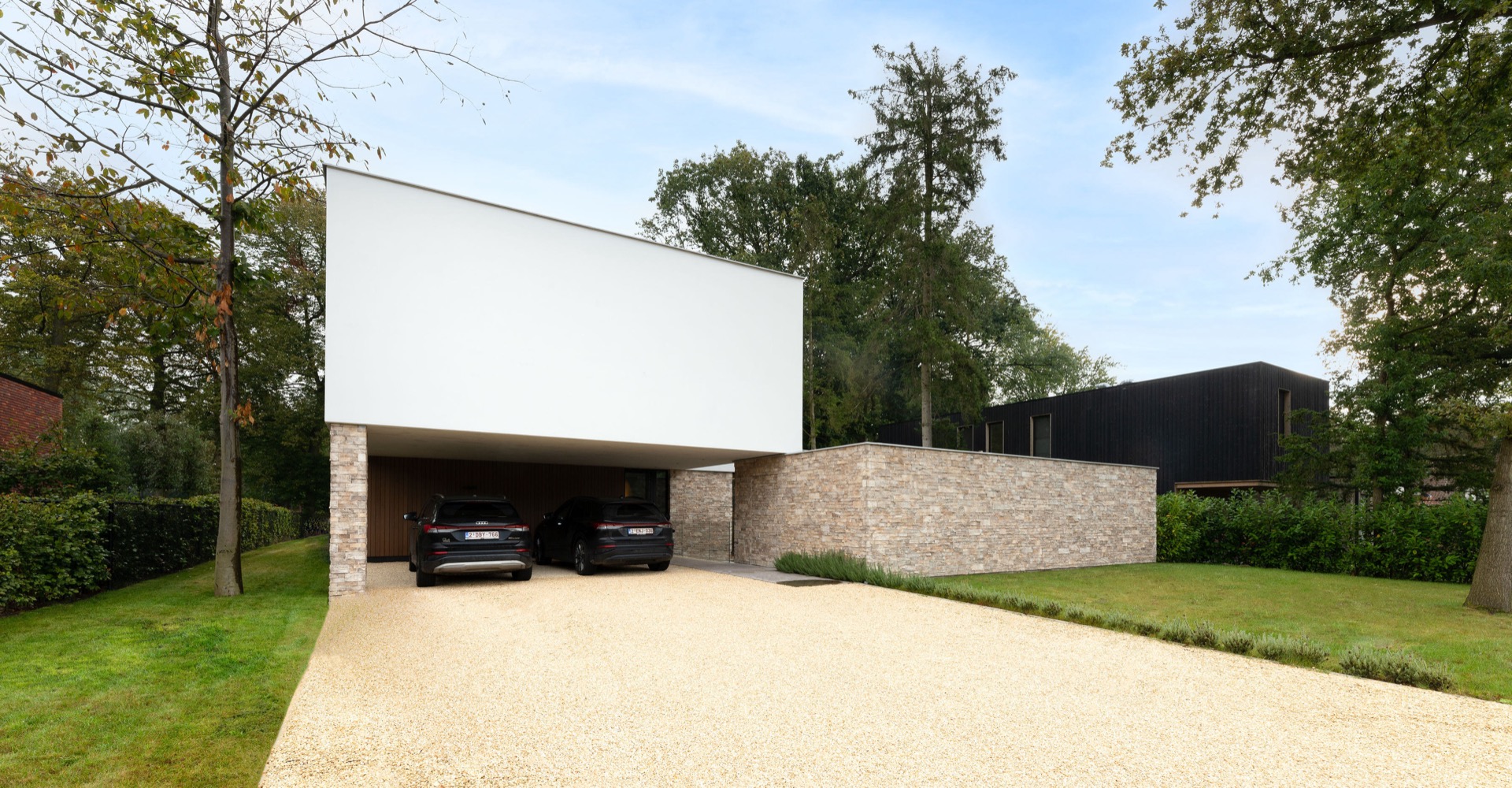 rivestimento in pietra naturale: vista laterale con apertura del carport, muro in pietra naturale e volumi bianchi moderni, Luxury, Design, Exclusive, Modern, Custom Made, Special, Beautiful