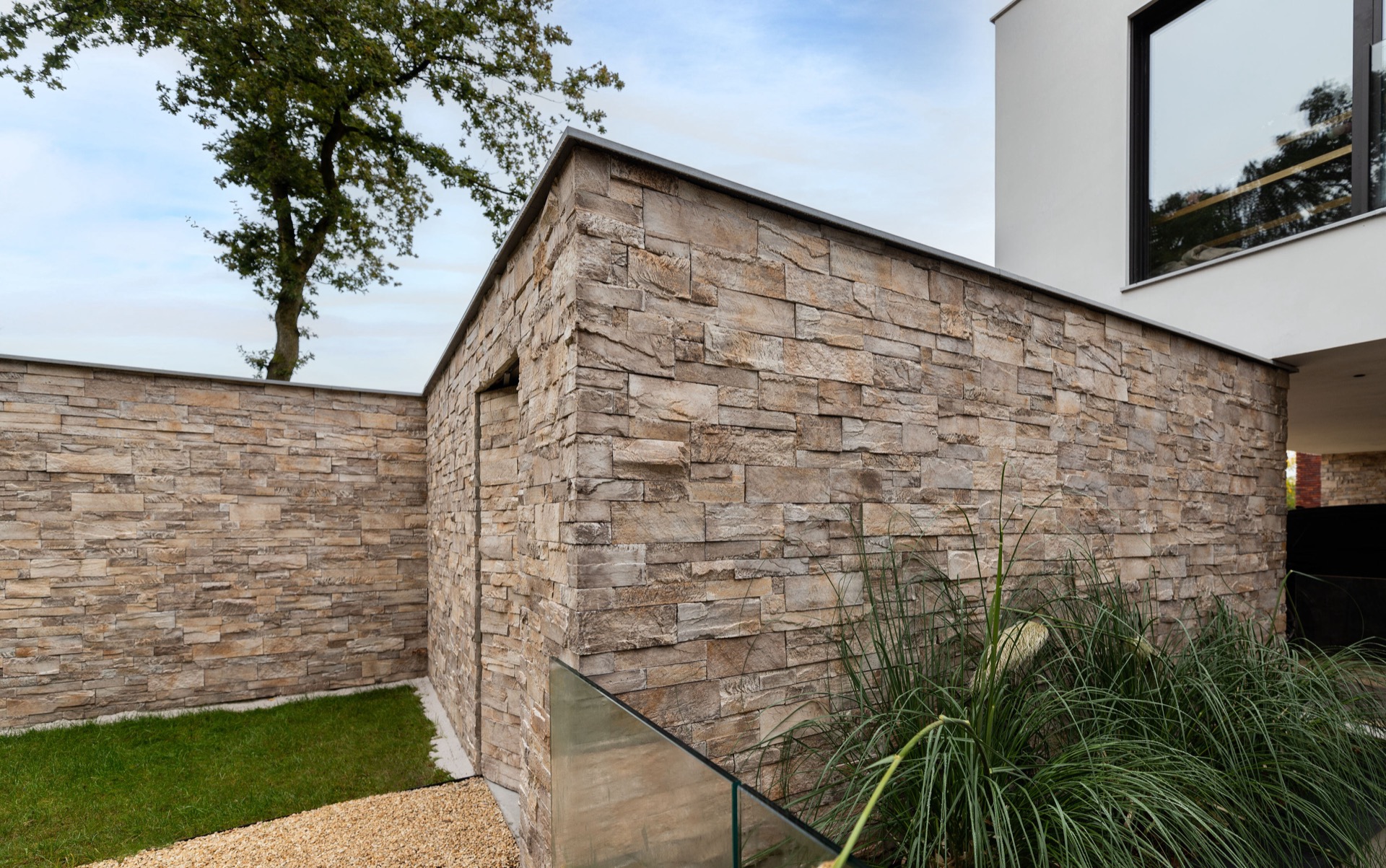rivestimento in pietra naturale: vista della facciata con grandi pannelli in vetro e basamento in pietra naturale di una, Luxury, Design, Exclusive, Modern, Custom Made, Special, Beautiful