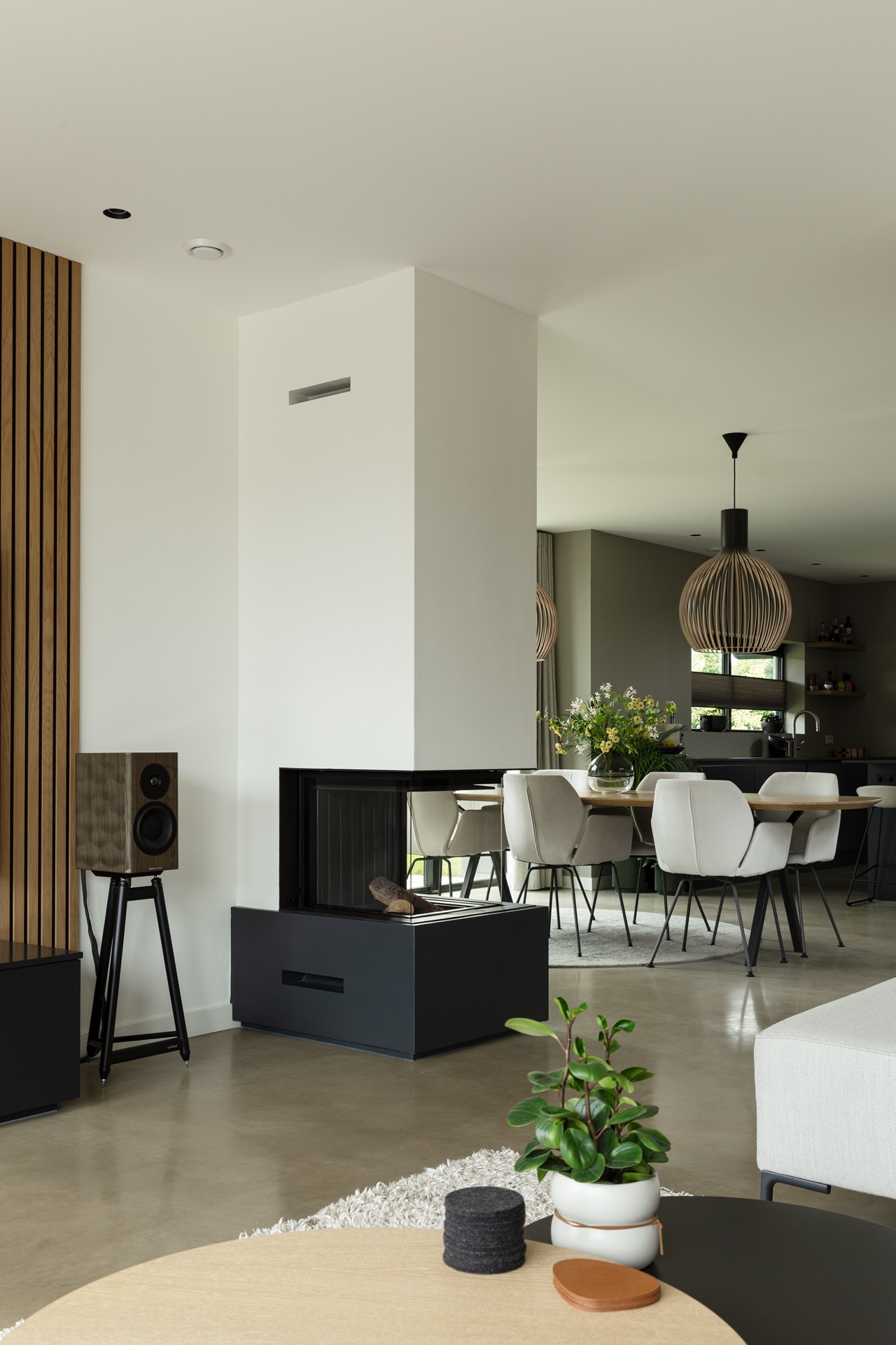 concrete floor in detached house: open-plan living space with fireplace, pendant lights, and continuous light grey concrete, Luxury, Design, Exclusive, Modern, Custom Made, Special, Beautiful