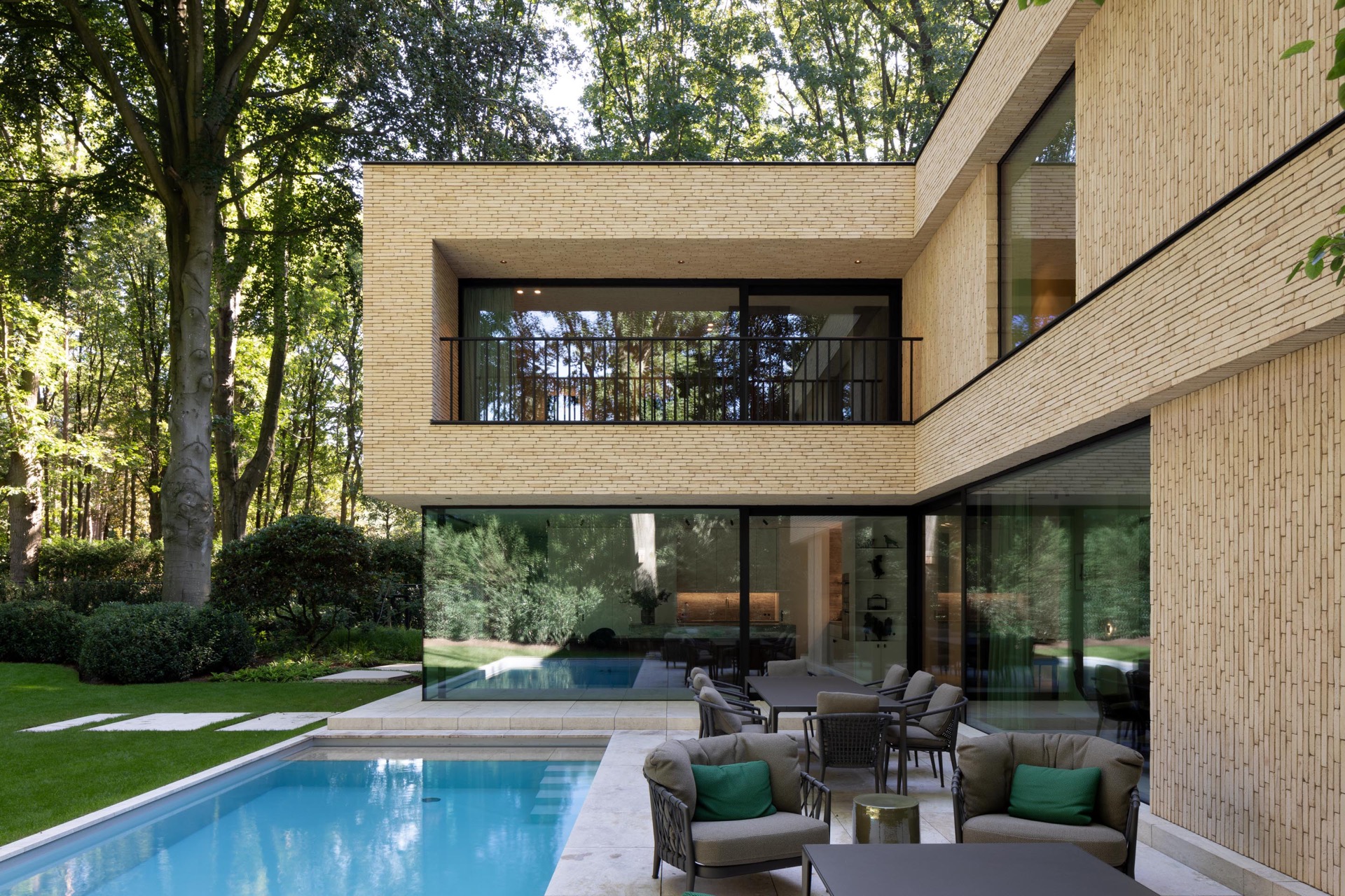 villa moderna in mattoni beige: galleria e balcone illuminati con ringhiera in metallo su villa beige al crepuscolo, Luxury, Design, Exclusive, Modern, Custom Made, Special, Beautiful