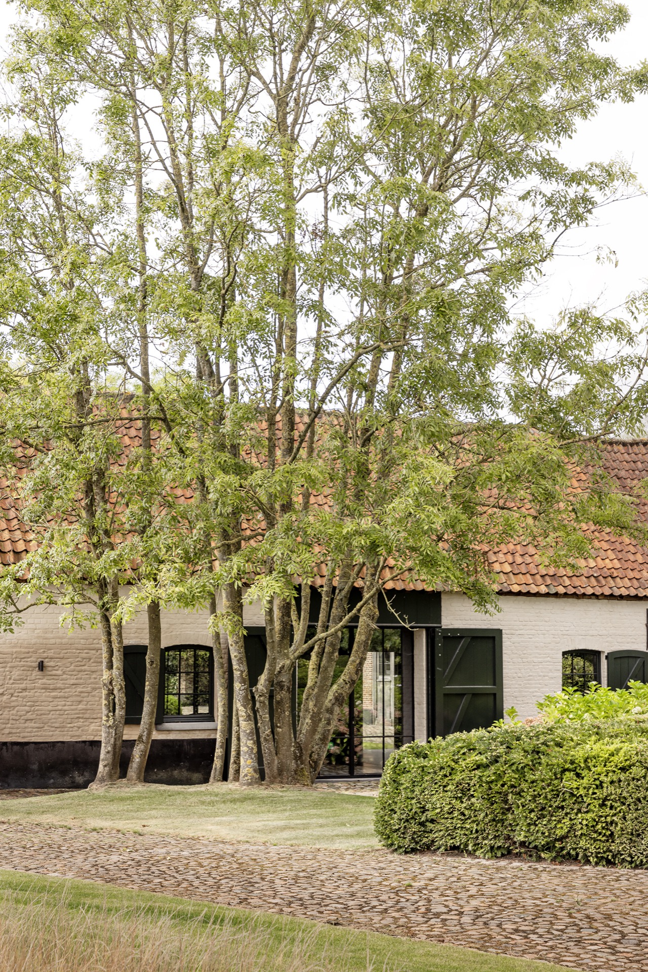 landscape garden sightline: brick facade with red roof tiles visible between tree canopies, Luxury, Design, Exclusive, Modern, Custom Made, Special, Beautiful