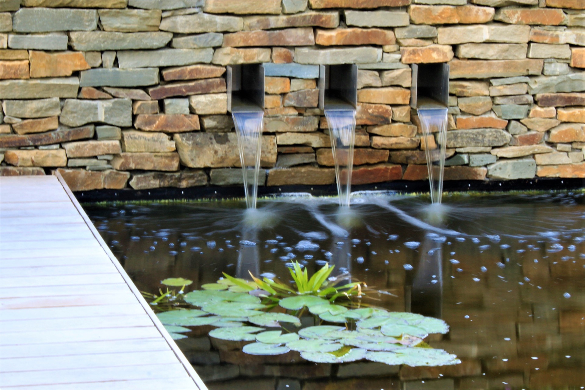 giardino moderno con laghetto e cascata: dettaglio cascata: flussi d’acqua da una parete in pietra naturale nel laghetto con, Luxury, Design, Exclusive, Modern, Custom Made, Special, Beautiful