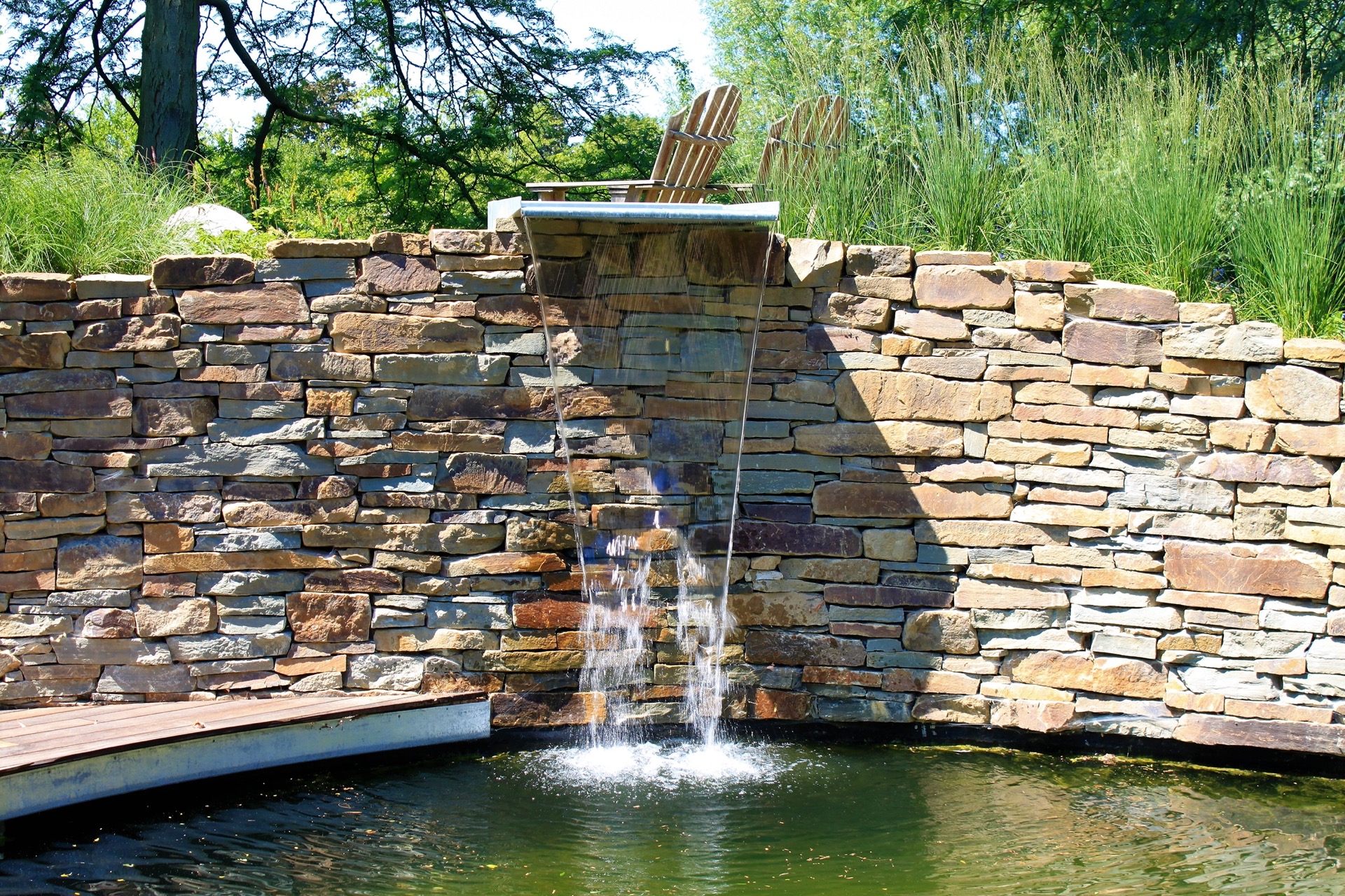 vasca da nuoto naturale con cascata: lettini vicino alla vasca da nuoto con cascata e muro in pietra naturale, Luxury, Design, Exclusive, Modern, Custom Made, Special, Beautiful