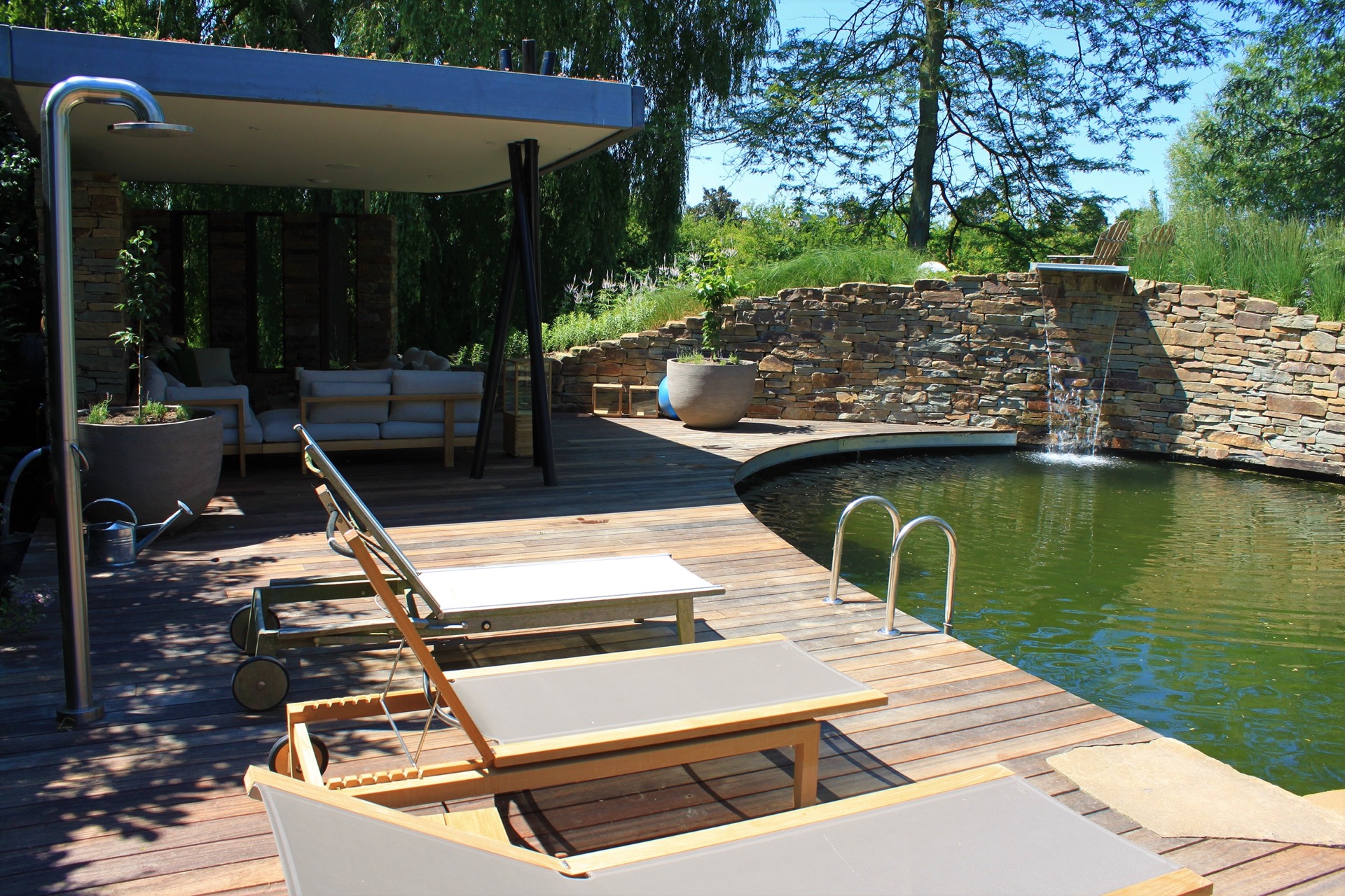 vasca da nuoto naturale con cascata: vista ampia di una vasca da nuoto con terrazza in legno, tettuccio e bordo fiorito, Luxury, Design, Exclusive, Modern, Custom Made, Special, Beautiful